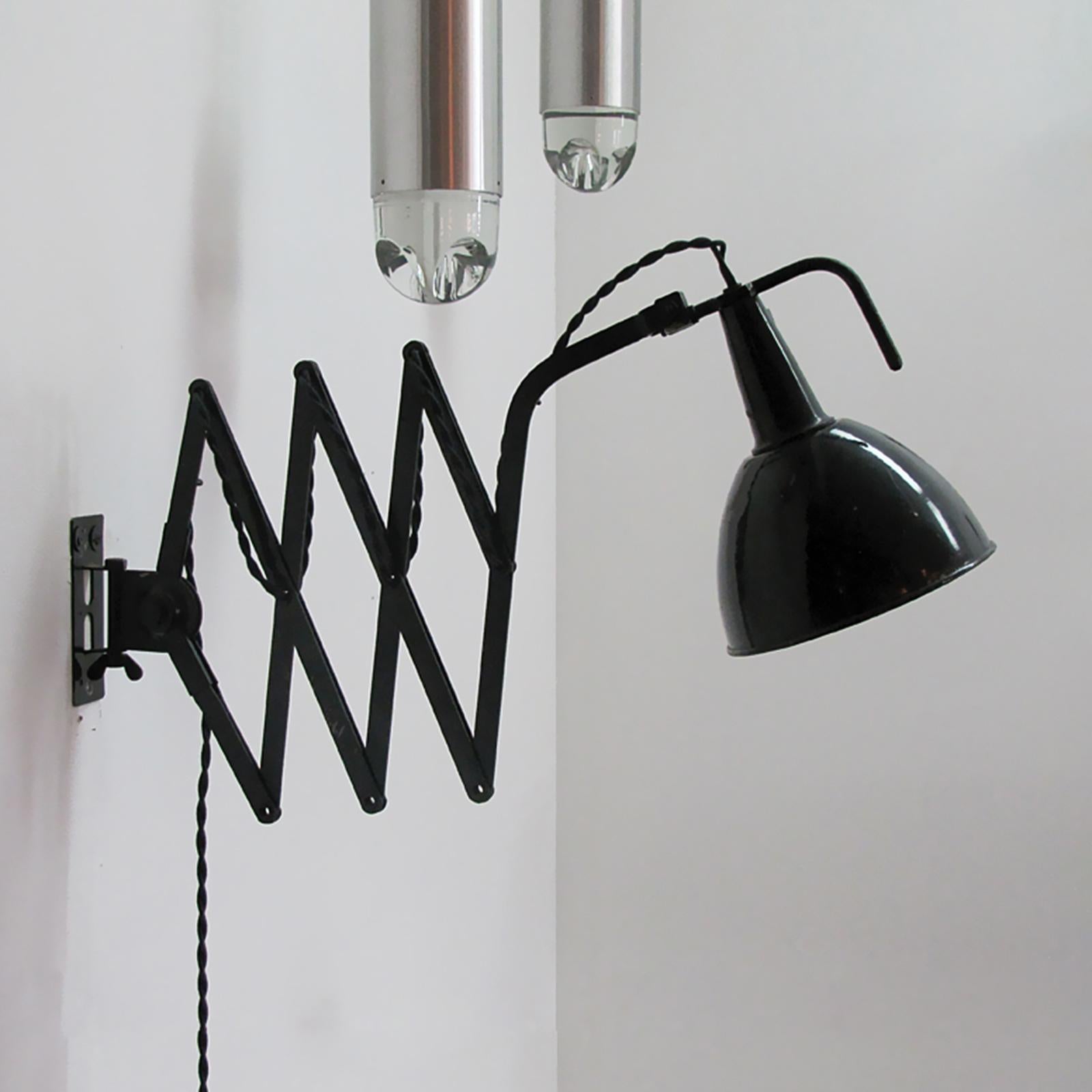 Articulating black enameled metal scissor wall lamp by Wilhelm Bader, extends from 14