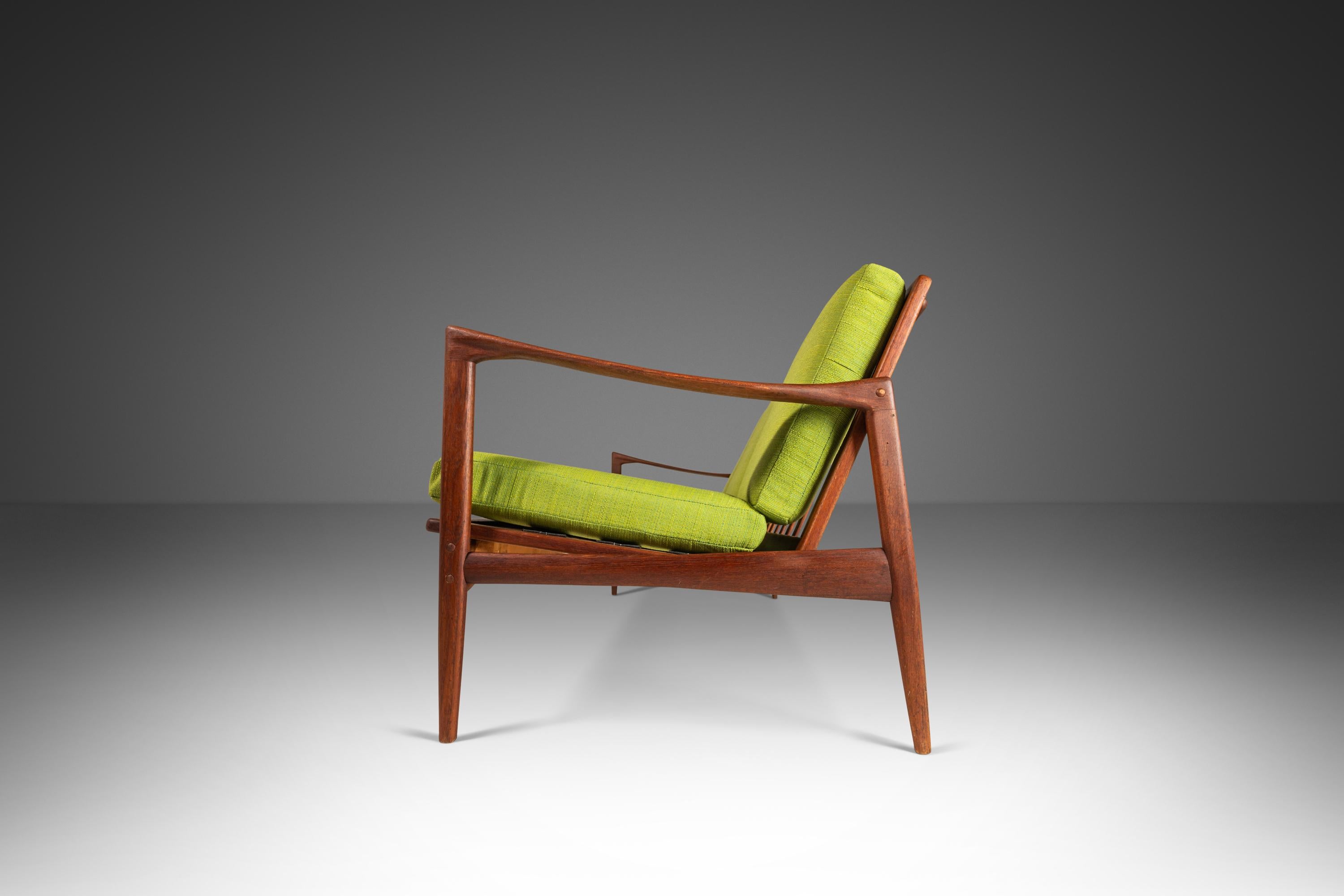 Das dreisitzige Sofa Kandidaten wurde von Ib Kofod-Larsen entworfen und 1962 in Schweden von Olof Perssons Fatoljindustri (O.P.E.) hergestellt. Dieses ikonische Design aus massivem Teakholz zeichnet sich durch zylindrische, konisch zulaufende Beine
