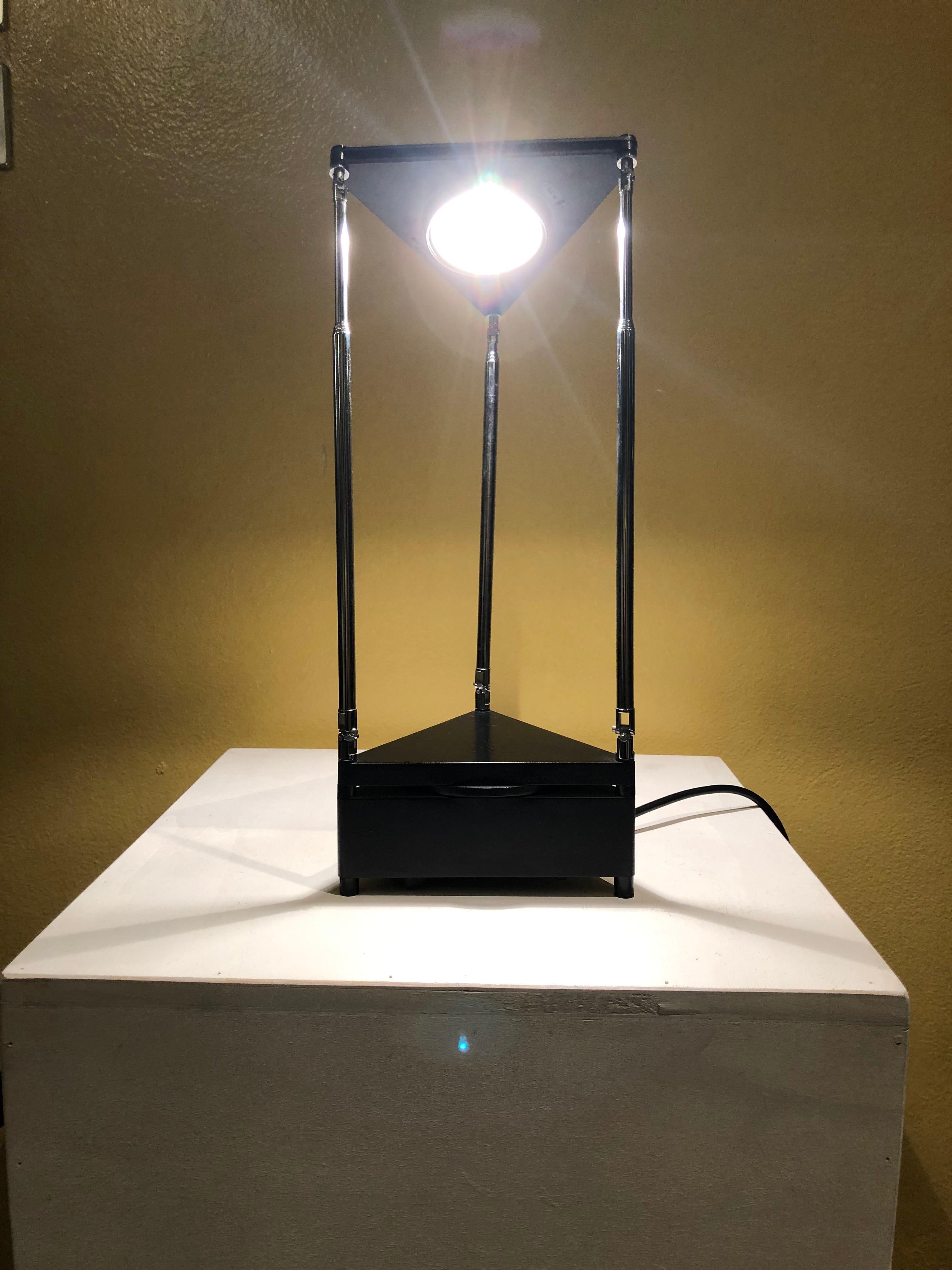 Kandido table lamp was designed by Ferdinand Alexander Porsche in 1983 for Luci Italia. This halogen table lamp has a black-lacquered metal stand and chromed telescopic arms that can move in all directions. It features a moulded black shade, and the