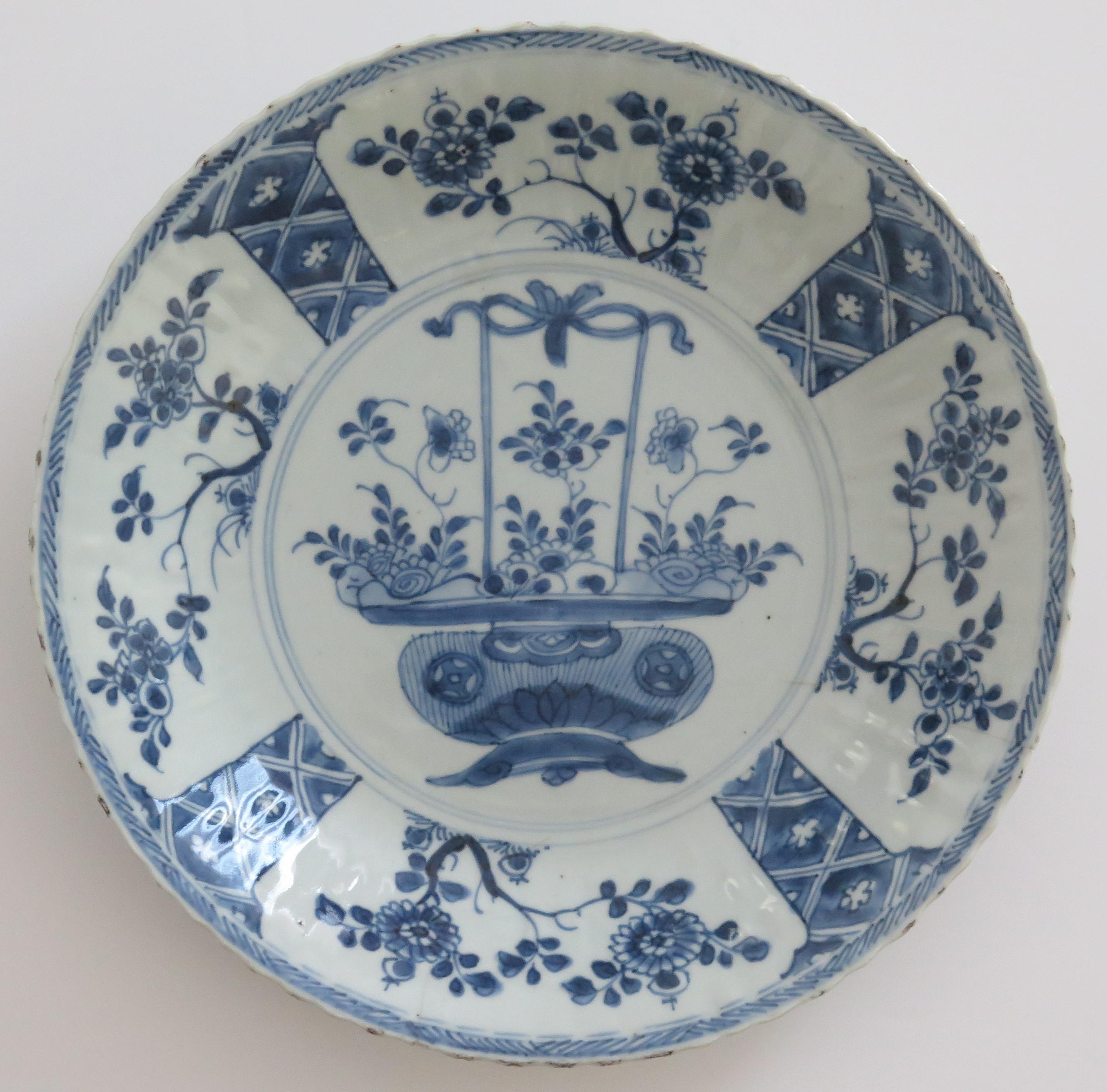 This is a beautifully hand-painted Chinese Export porcelain blue and white, large deep plate or dish which we date to the Qing, early 18th Century, Yongzheng period, Circa 1730.

The plate is finely potted with a ribbed cavetto and frilled rim edge,