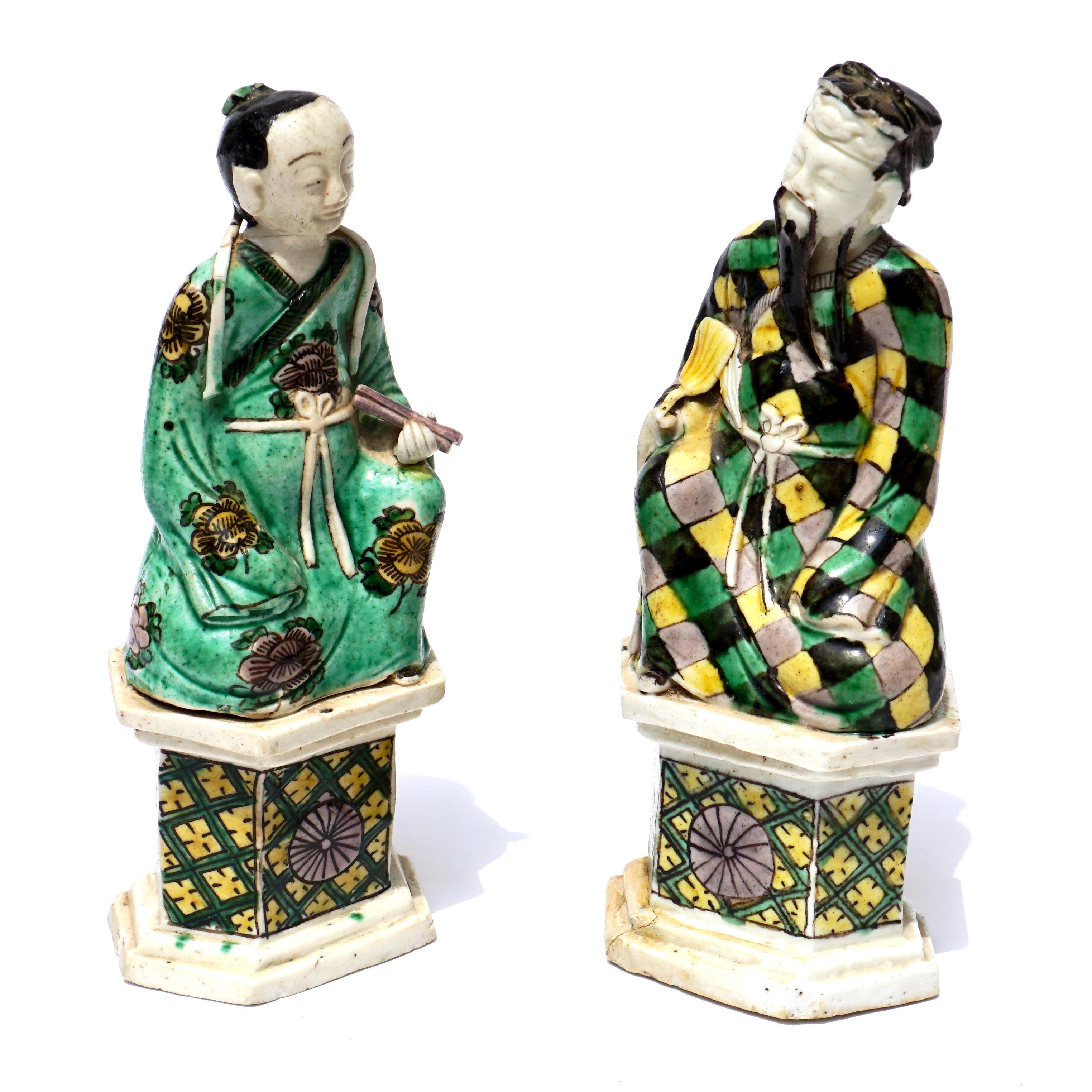 Two Chinese Famille Verte figures of the Immortals Zhong Li Quan and Lan Cai He, Kangxi, coloured with green, yellow, black and aubergine glazes, raised on hexagonal bases, Zhong Li Quan holding his fan and Lan Cai He with castanets, with Radcliffe