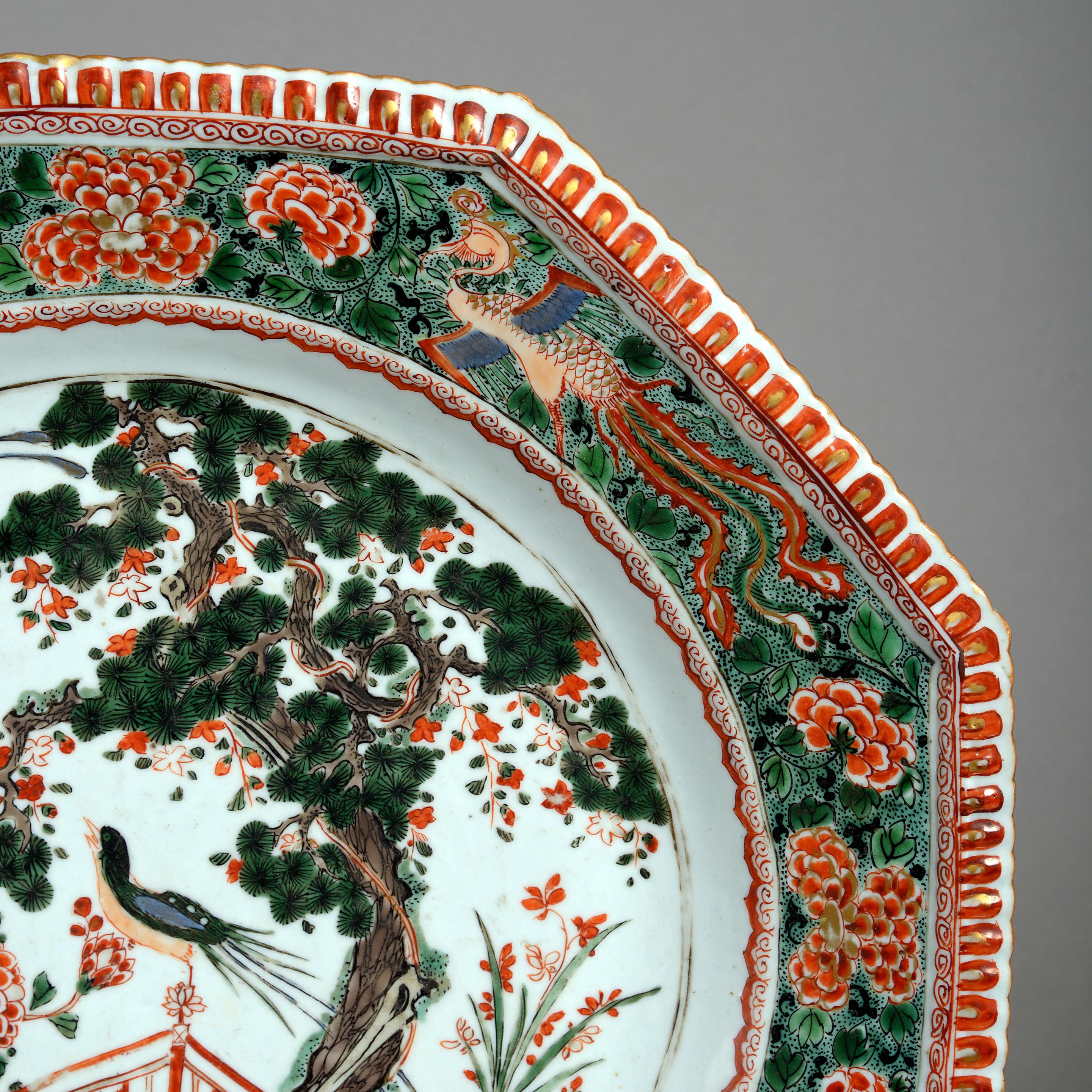 A Kangxi period Famille Verte porcelain octagonal charger having a richly painted border about a central cartouche depicting exotic birds within an imaginary landscape. 

Condition: Restored.
