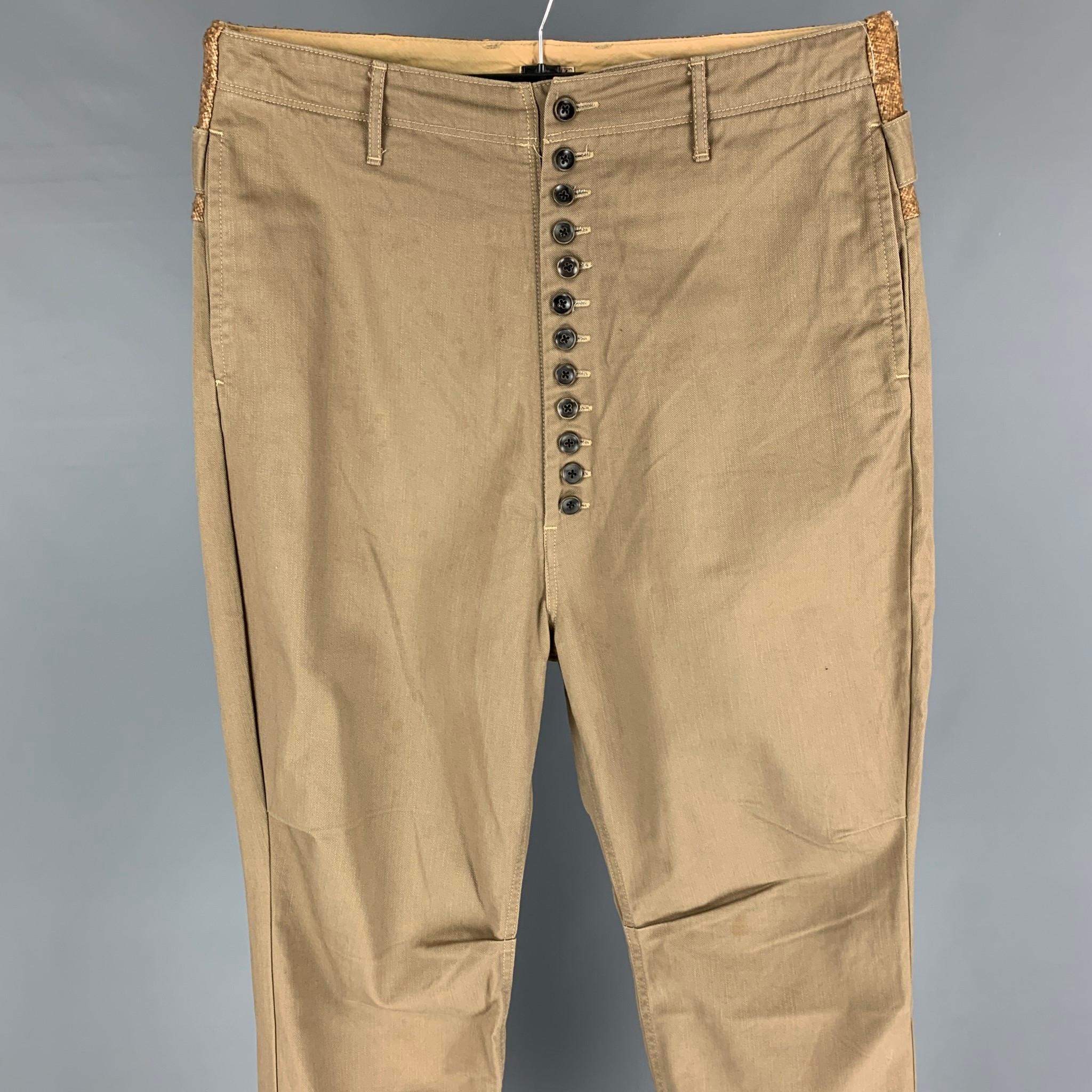 KAPITAL casual pants comes in a khaki cotton featuring a high waisted style, slim fit, wool panel, back strap detail, contrast stitching, and a button fly closure. 

Good Pre-Owned Condition. Discoloration at front.
Marked: 3

Measurements:

Waist: