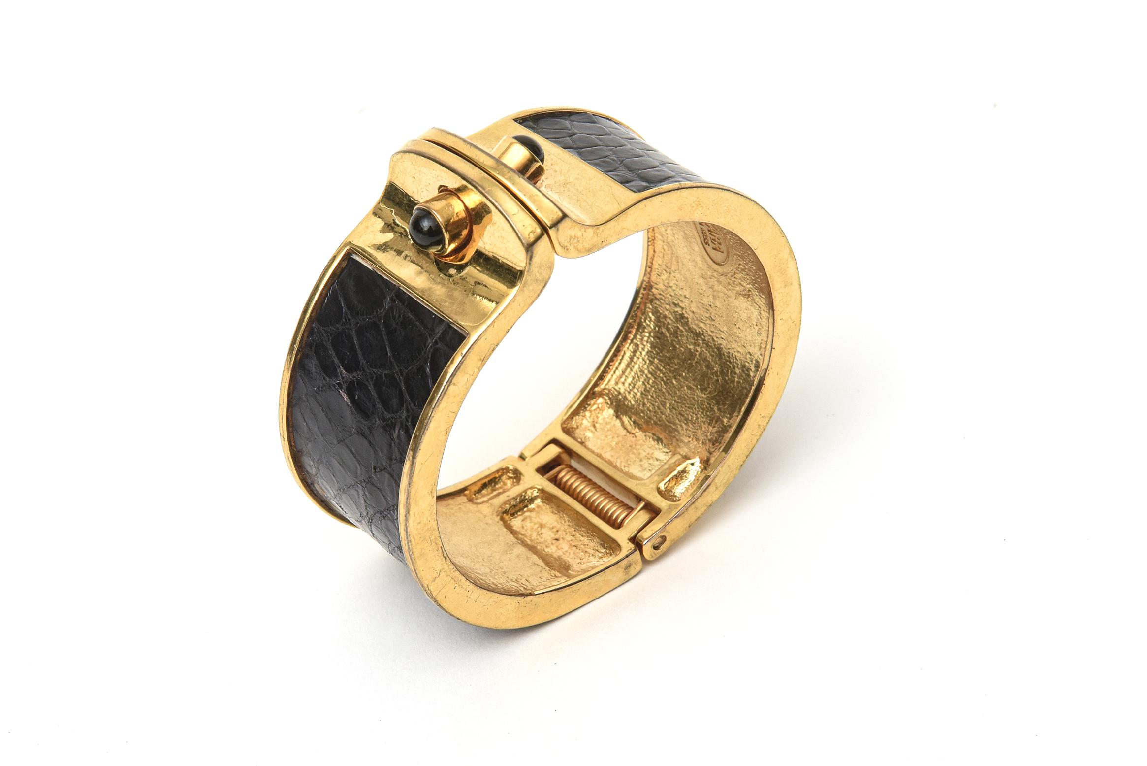 This lovely modernist Kara Ross hinged cuff bracelet is from the 90's. It is marked on the inside. The stamped snakeskin leather is black with gold plating and glass stones. It has good weight on and will fit best a wrist size of 6.5 or 7