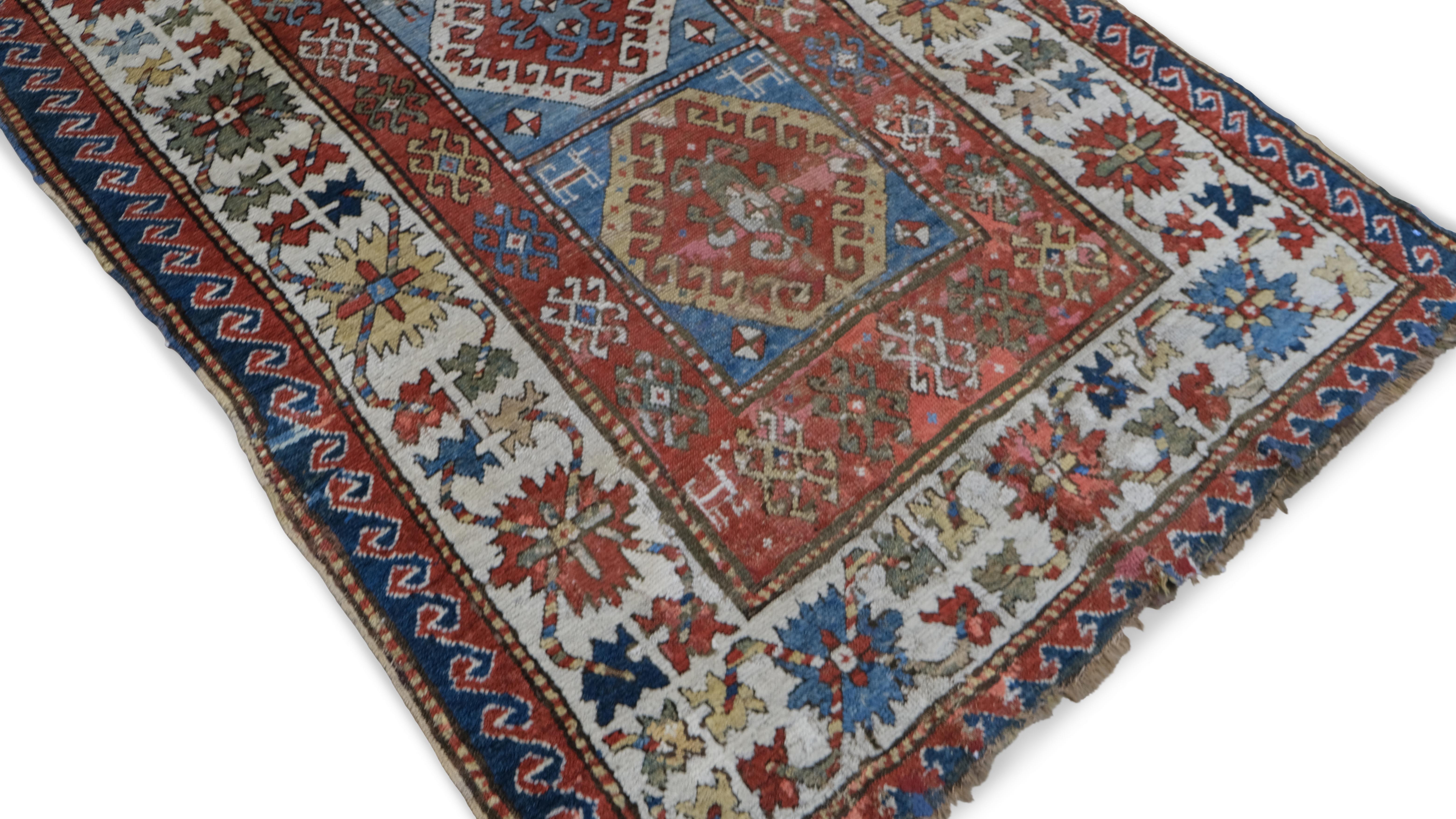 Dieser antike, handgeknüpfte Wollläufer ist ein eindrucksvolles Beispiel für die traditionelle kasachische Weberei mit kühnen geometrischen Motiven, leuchtenden Farben und verschlungenen Stammesmustern. Das zentrale Feld ist mit einer Reihe von