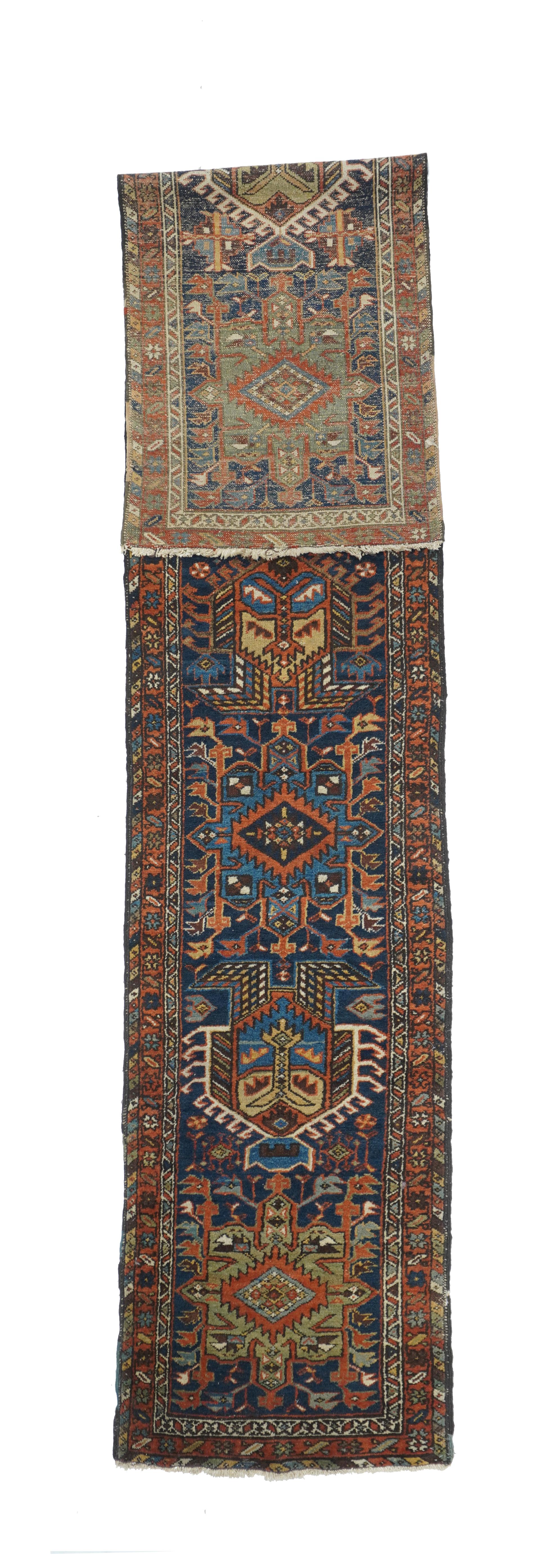 The blue field of this rust ic NW Persian runner displays seven characteristic octogrammes and hooked complex abstract palmette medallions, with ecru, green and medium blue accents. The red border shows stars and oblique bars. Moderate weave on