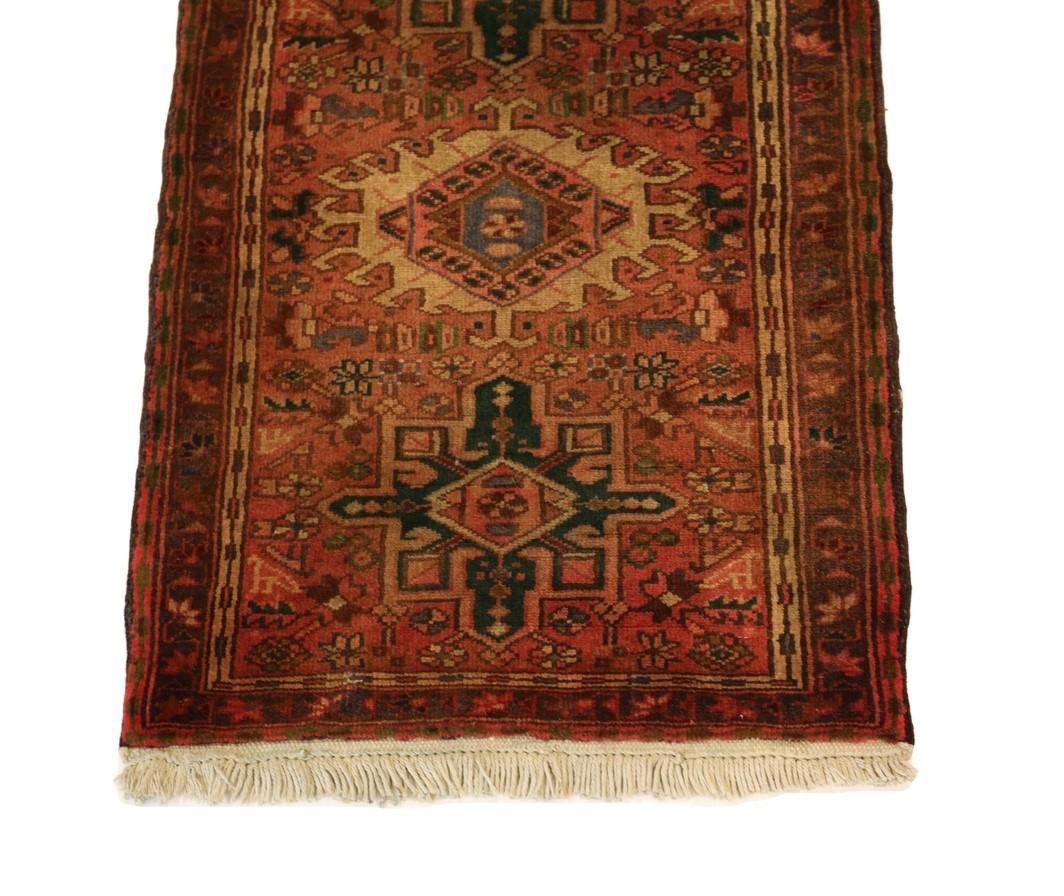 Introducing the exquisite Kareje Runner, a unique and captivating tapestry that seamlessly blends tradition with a touch of whimsy. This handmade rug features a striking red background, adorned with an alternating medallion pattern that adds a