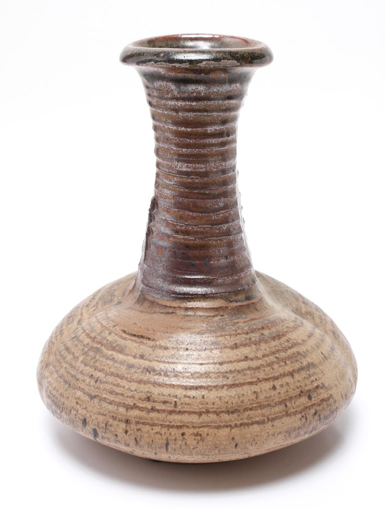 American Mid-Century Modern stoneware art pottery vase designed by Karen Karnes (American, 1925-2016), with a rolled lip and tapering ribbed neck and a brown-green glaze. The piece is signed with an impressed artist's monogram 