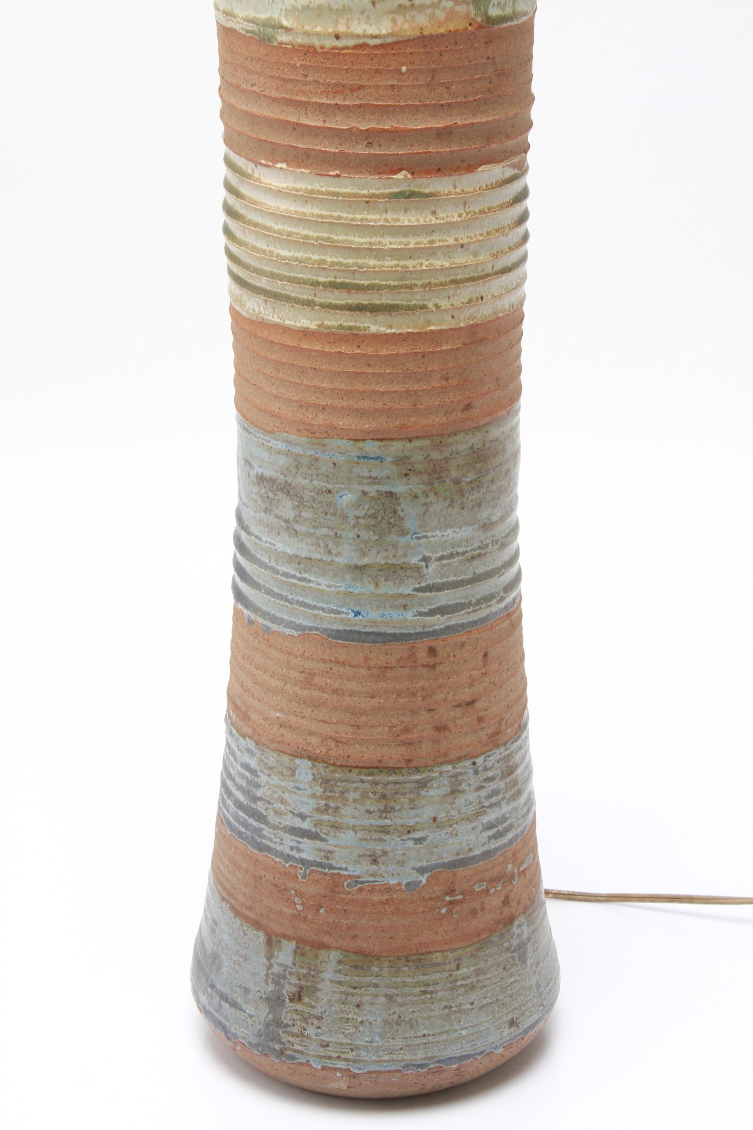 Amerikanische Mid-Century Modern Steingut Kunst Keramik Tischlampe entworfen von Karen Karnes, (Amerikaner, 1925-2016). Das Stück hat eine polychrome Glasur mit abwechselnden horizontalen Bändern und ist auf der Unterseite mit einem eingeprägten