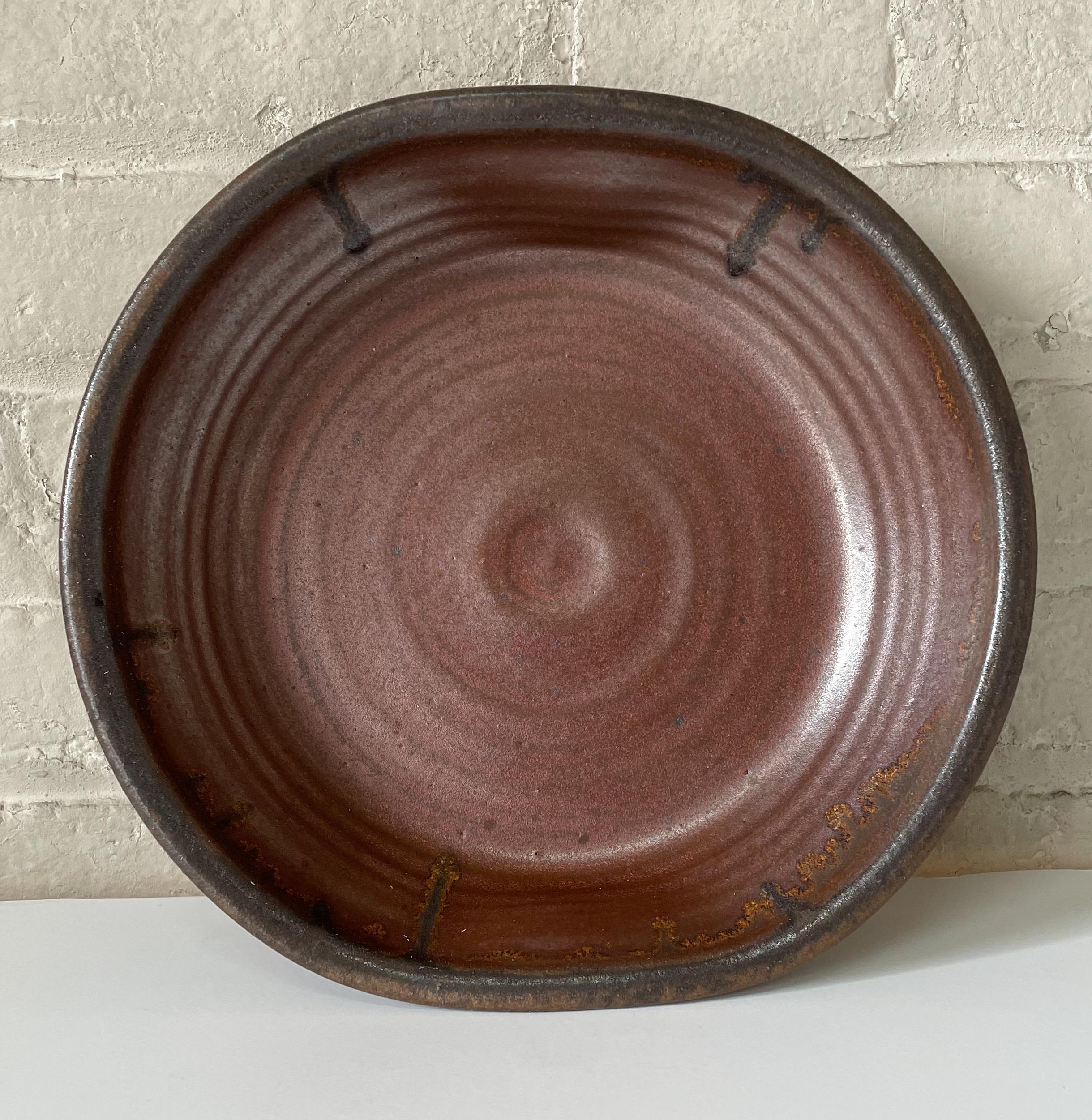 Hand-turned and glazed vessel of wood-fired stoneware by renowned American studio potter Karen Karnes. Drip overglaze blends brown with reddish brown and copper colors; lip and shoulder are pinched on opposite sides, creating an eccentric form.
