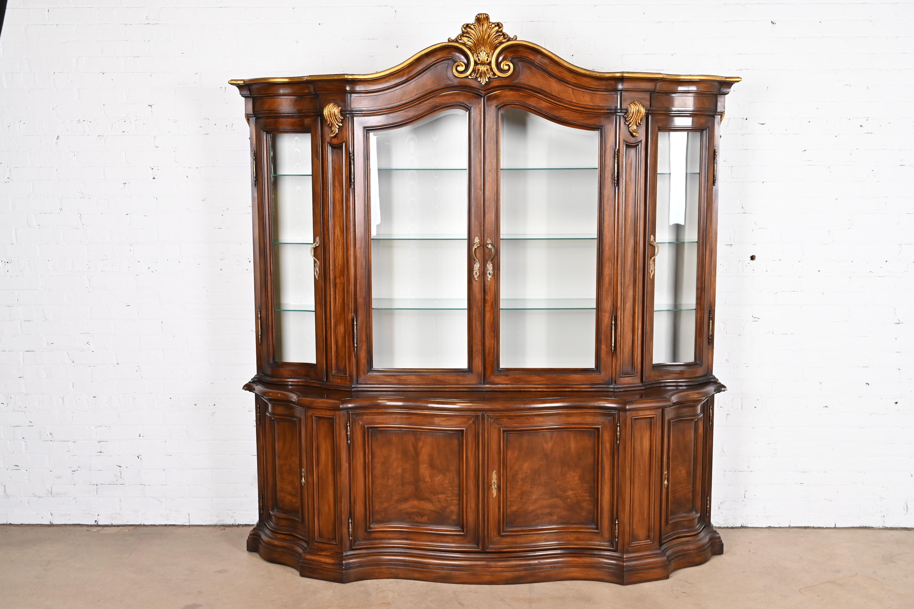 A gorgeous French Provincial Louis XV style lighted breakfront bookcase or dining cabinet

By Karges Furniture

USA, Circa 1980s

Carved burled walnut, with gold gilt details, glass front doors, and original brass hardware. Cabinet locks, and key is