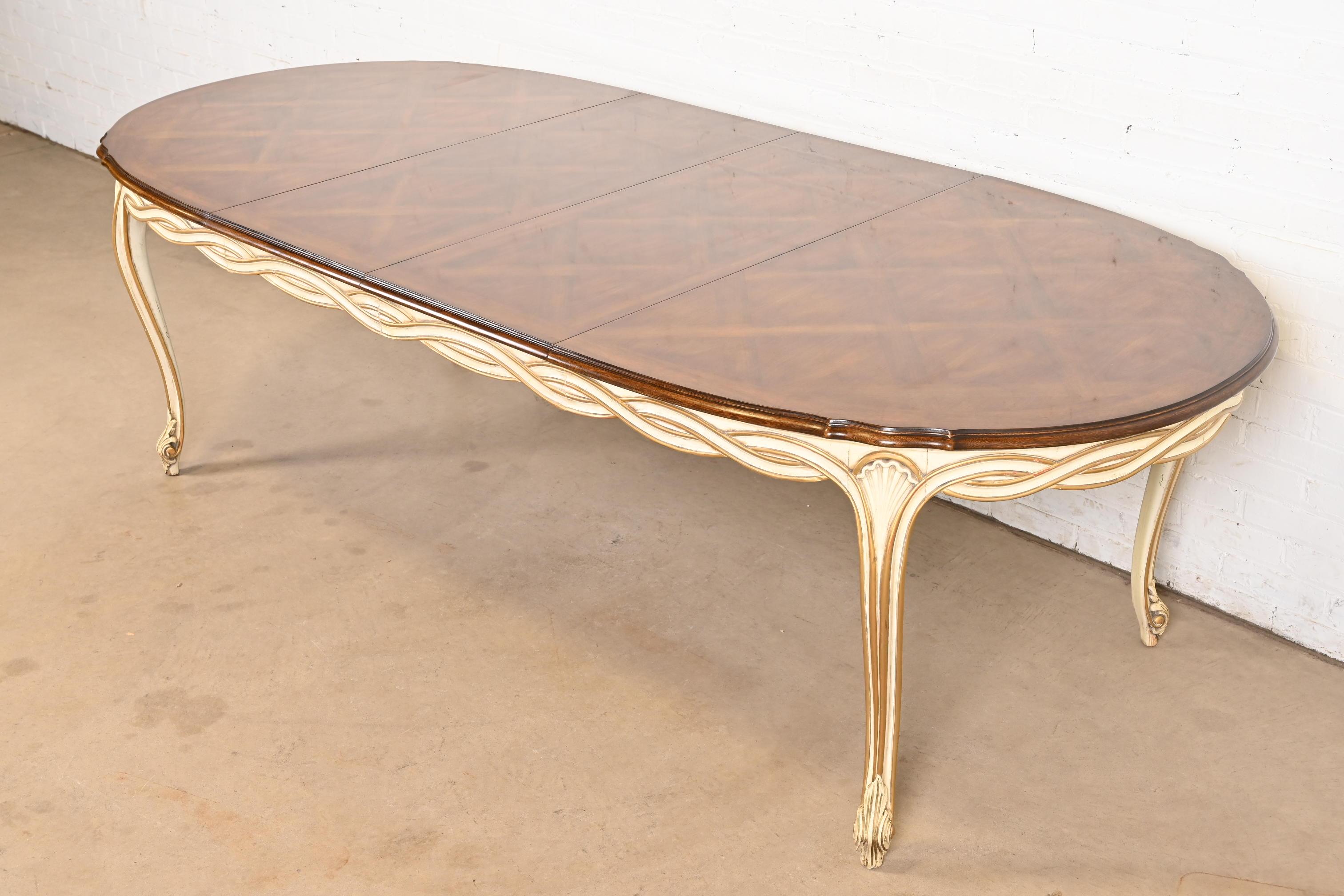 An exceptional French Rococo or French Provincial Louis XV style extension dining table

By Karges Furniture

USA, Circa 1960s

Walnut top with inlaid parquetry, and cream lacquered and gold gilt apron and legs.

Measures: 63.5