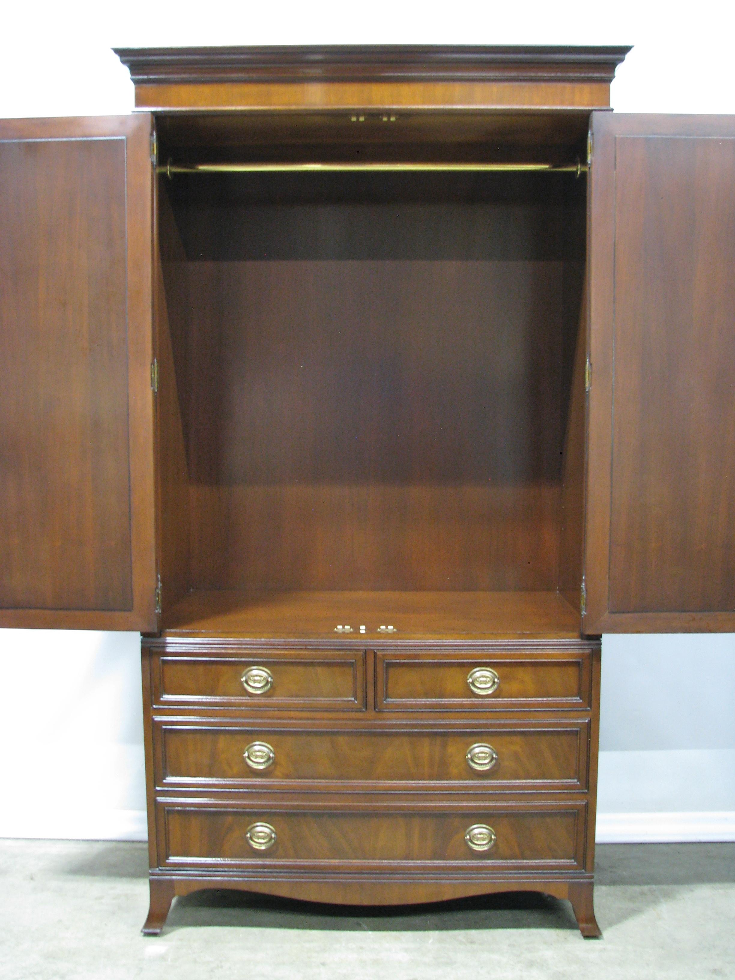 18th century style American armoire by luxury furniture brand Karges. Constructed of Mahogany solids with beautifully figured mahogany veneers. Tall upper cabinet, with locking doors featuring an oval inlay. The interior is fitted with a brass rod