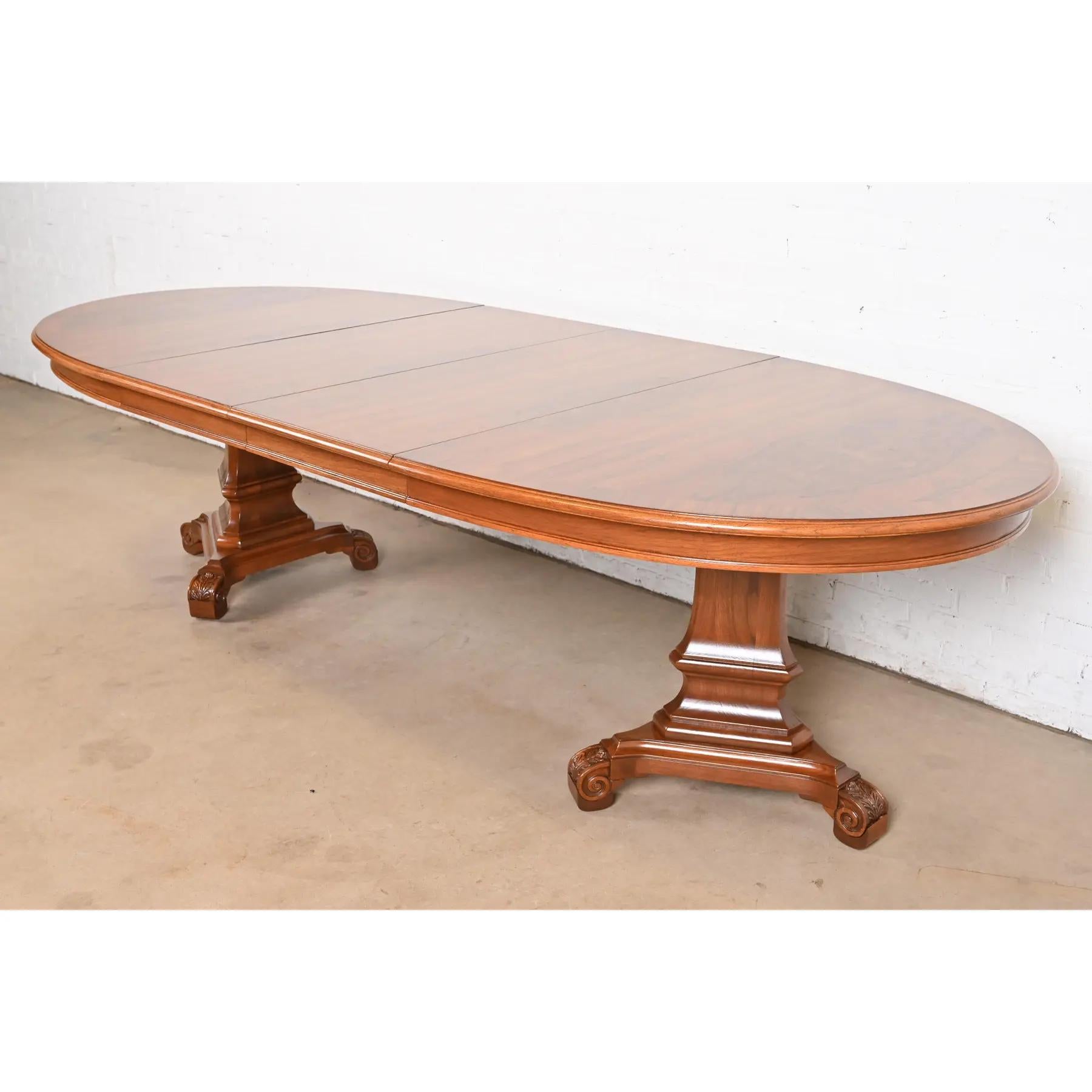 Una excepcional mesa de comedor extensible de doble pedestal de estilo Regencia o Neoclásico

Atribuido a Karges Furniture

EE.UU., alrededor de 1960

Preciosa encimera de nogal burilado con bandas a juego, con pedestales de nogal tallado.

Medidas: