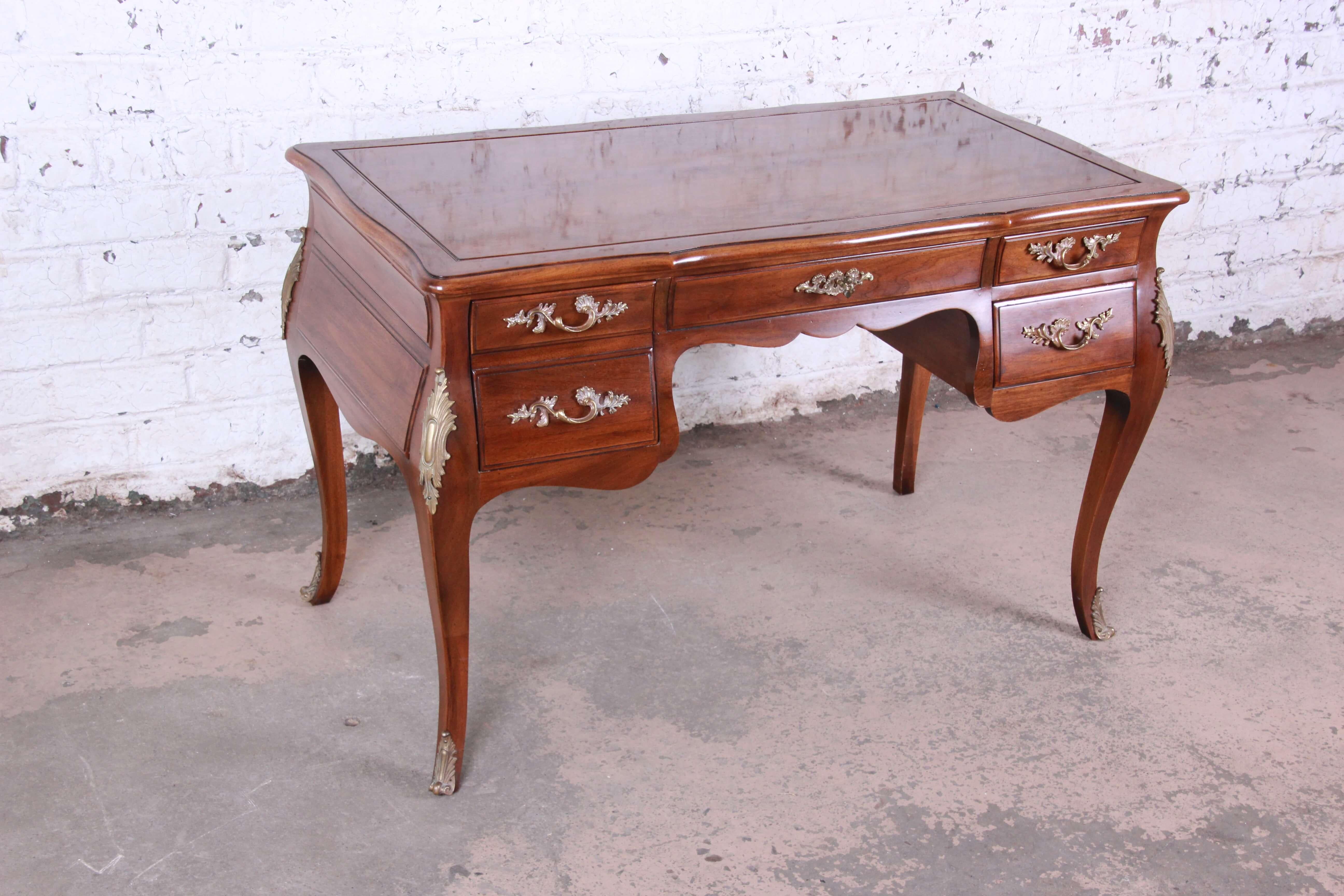 Offering an exceptional walnut French writing desk by Karges. This piece has stunning beauty with a burled walnut top and solid brass French pulls and ormolu. The writing desk offers a large file sized drawer on the left, a locking center drawer and