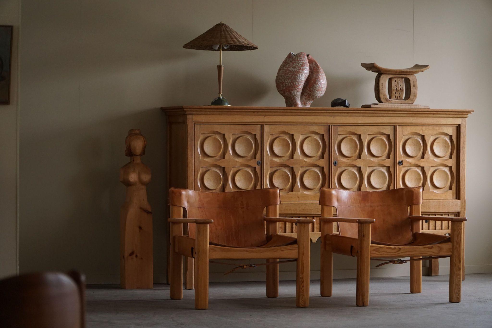 A pair of charming Swedish Mid Century Modern lounge chairs in solid pine, upholstered in leather with a lovely patina. Designed by Karin Mobring, model 