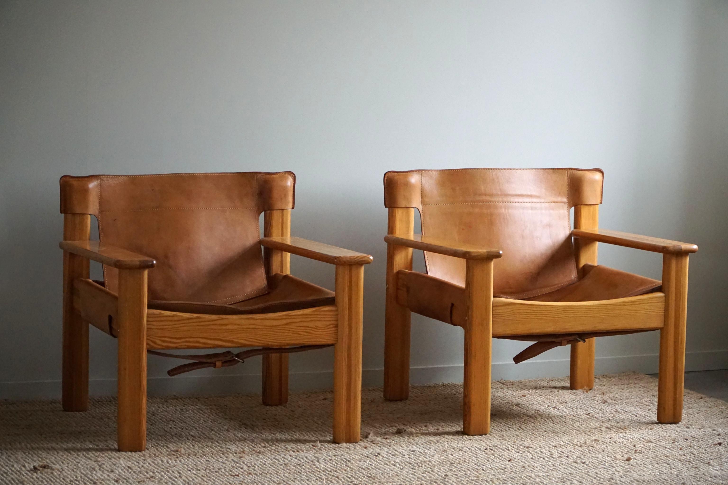 A pair of charming Swedish Mid Century Modern lounge chairs in solid pine, upholstered in leather with a lovely patina. Designed by Karin Mobring, model 