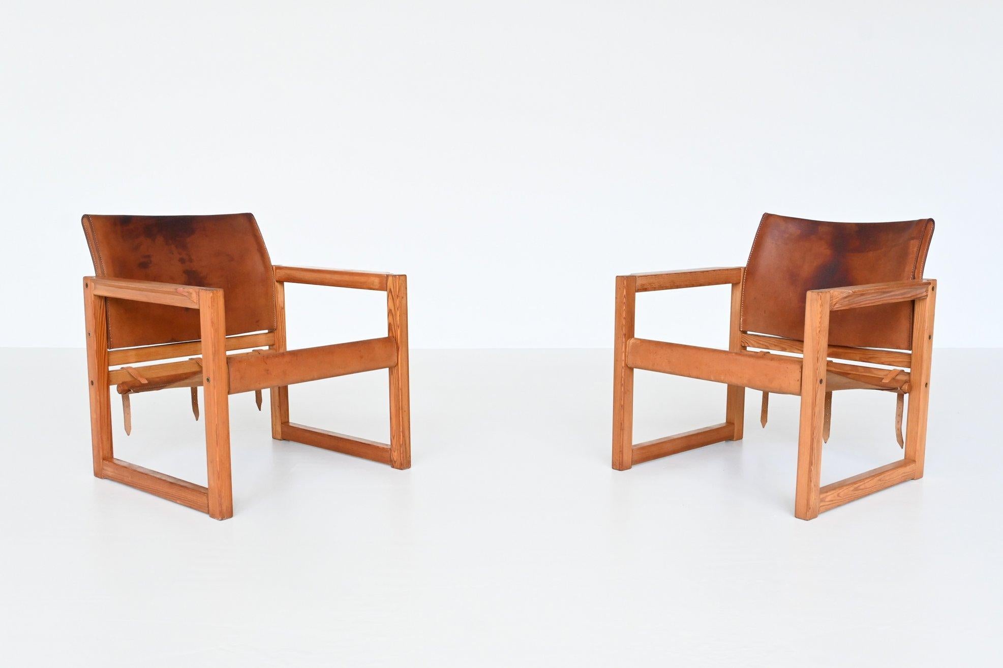 Beautiful elegant pair of Safari lounge chairs model Diana designed by Karin Mobring for IKEA, Sweden 1970. These chairs have a solid pine wooden frame with original cognac saddle leather seating. The straps at the back give the chairs a