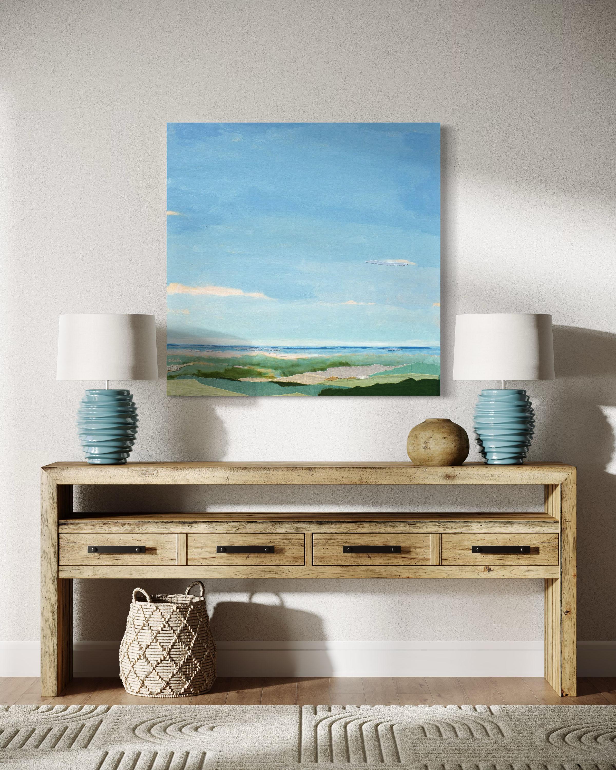 This contemporary abstract painting by Karin Olah, titled Beyond the Dunes, offers a tranquil view across soft rolling grasses and sandy textures toward a distant shoreline beneath an expansive blue sky. Layers of hand-dyed fabric and acrylic paint