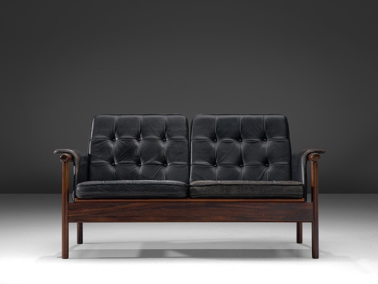 Karl-Erik Ekselius for JOC, sofa, leather and rosewood, Sweden, 1960s.

This sofa features a rosewood frame with slatted back and an angular, geometric frame. It features a tufted seat and back are comfortable and support the sitter. The backrest