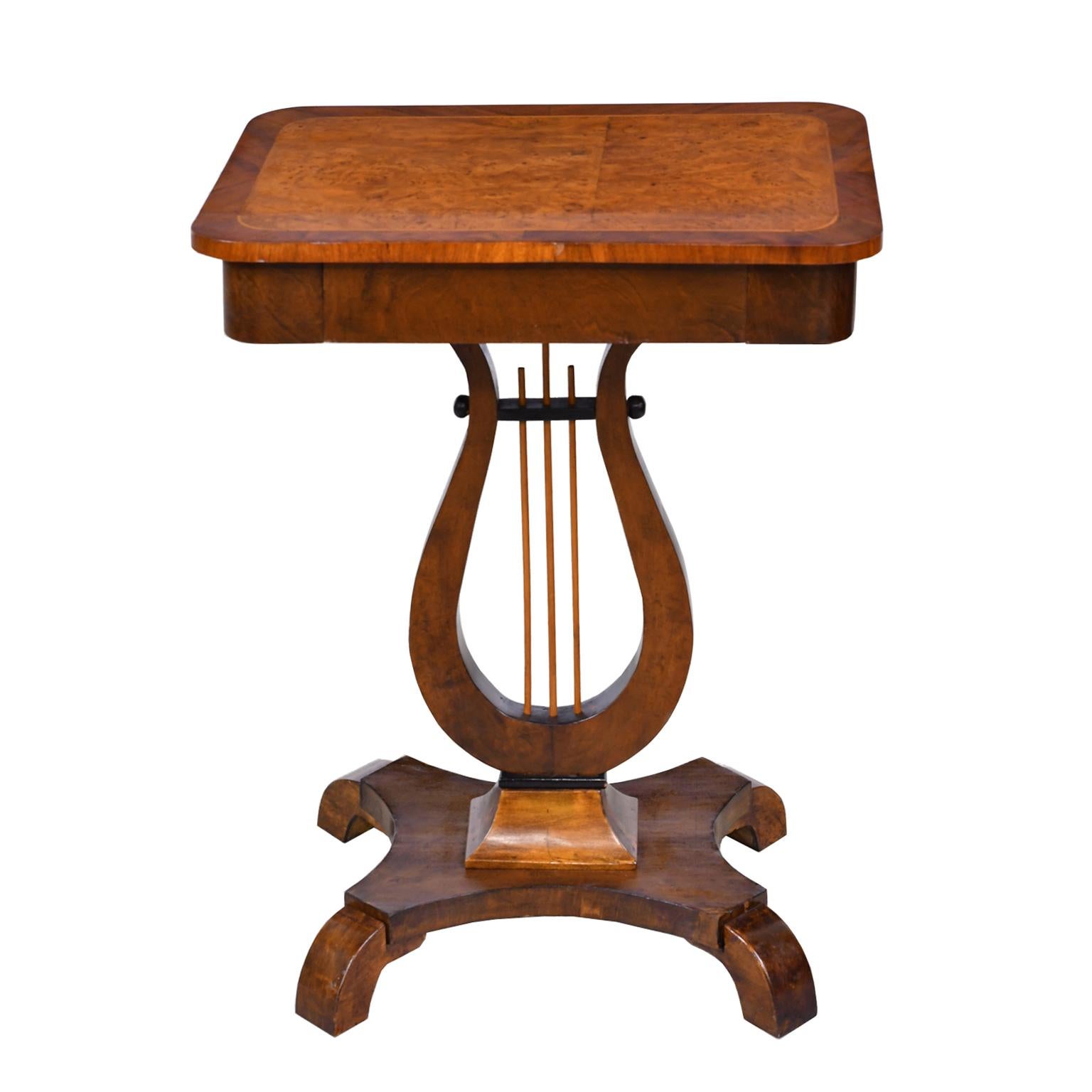 A graceful Karl Johan salon table in beautiful Birchwood with inlaid banding along edge of rectangular top and offering one drawer. The carved lyre-form pedestal rests on quatre-form base with inward scrolling feet. Sweden, circa