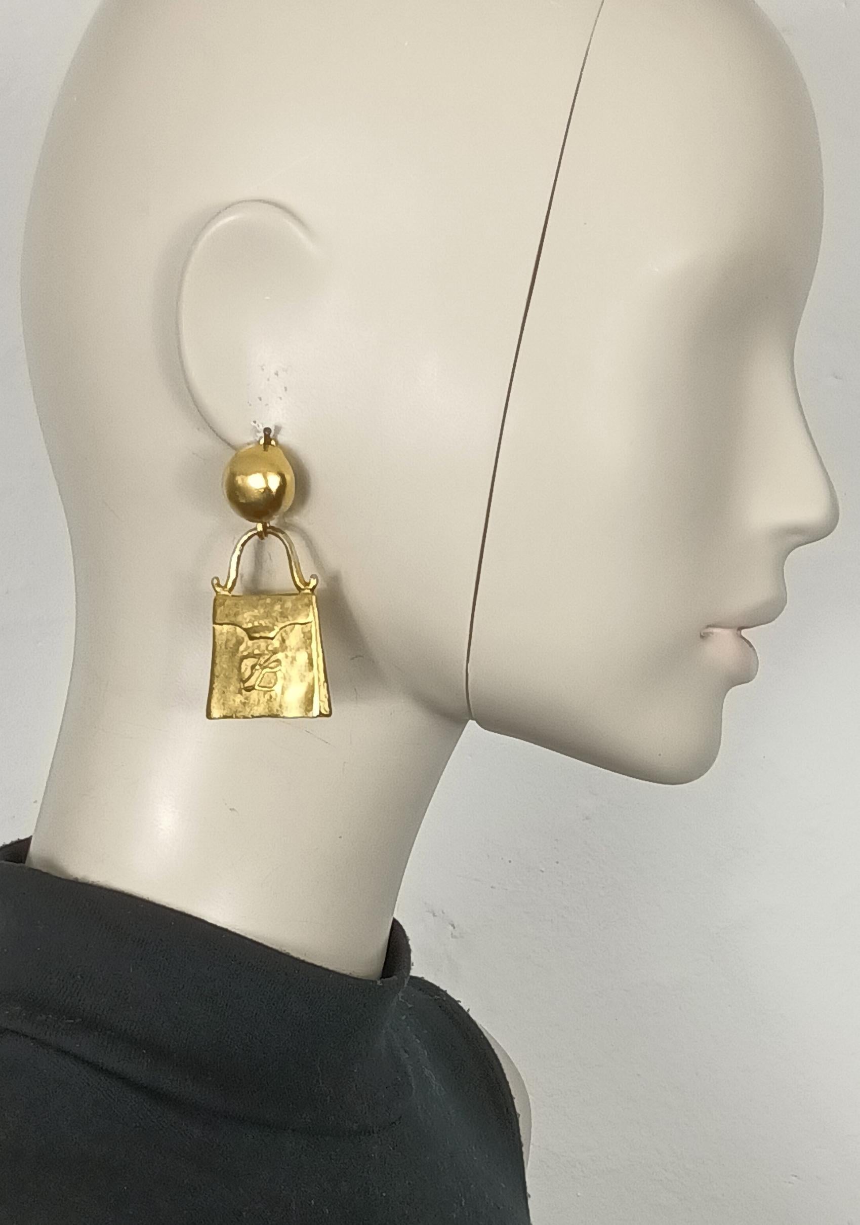 KARL LAGERFELD vintage gold tone novelty dangling earrings (clip-on) featuring a bag with KL logo.

Embossed KL on the reverse sides.

Indicative measurements : height approx. 5.7 cm (2.24 inches) / max. width approx. 2.8 cm (1.10 inches).

Weight