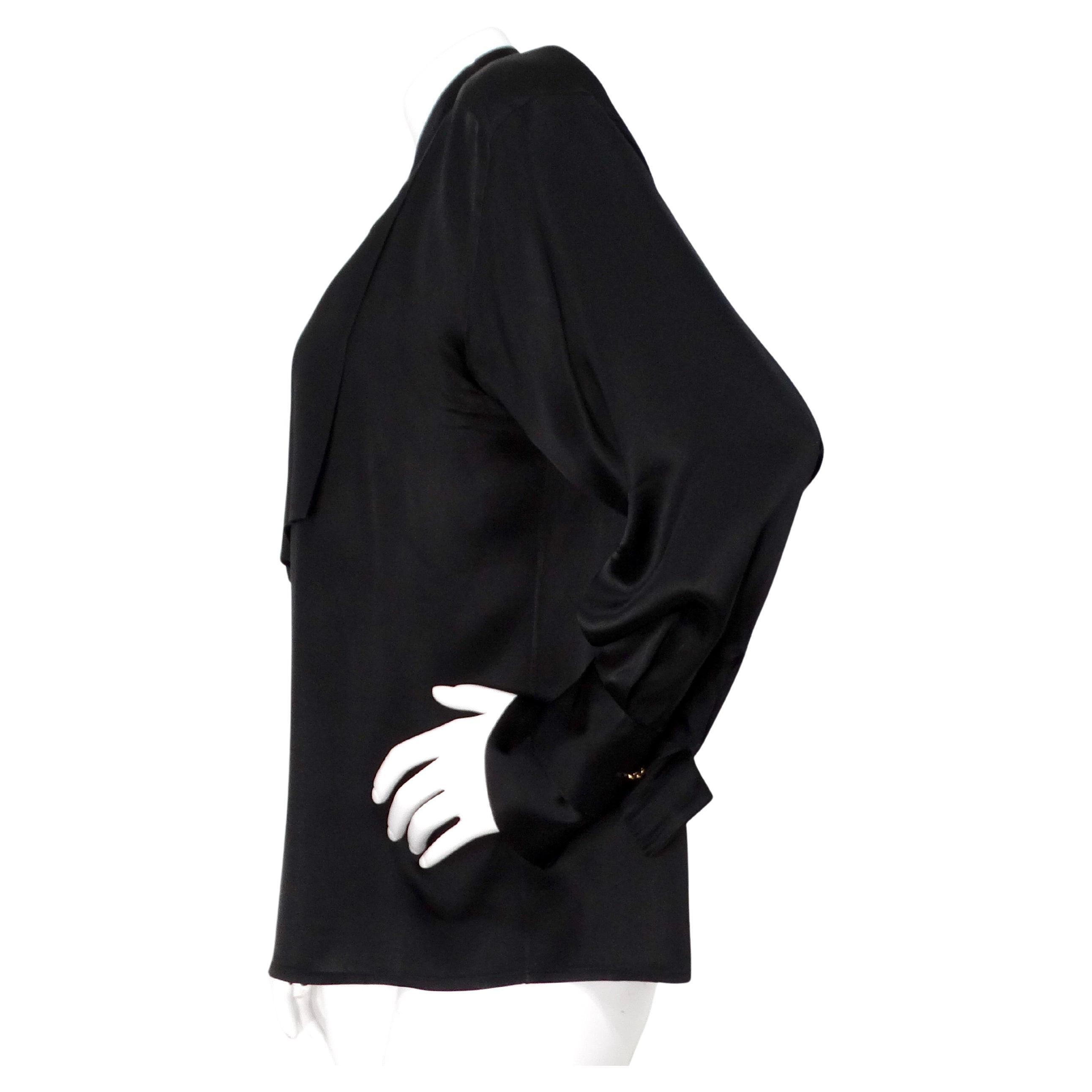 The Karl Lagerfeld Black Silk Button-Up Cufflink Blouse from the circa 1980s exemplifies timeless sophistication and elegant minimalism. Crafted from luxurious black silk, this blouse offers a sleek and smooth texture that drapes beautifully on the