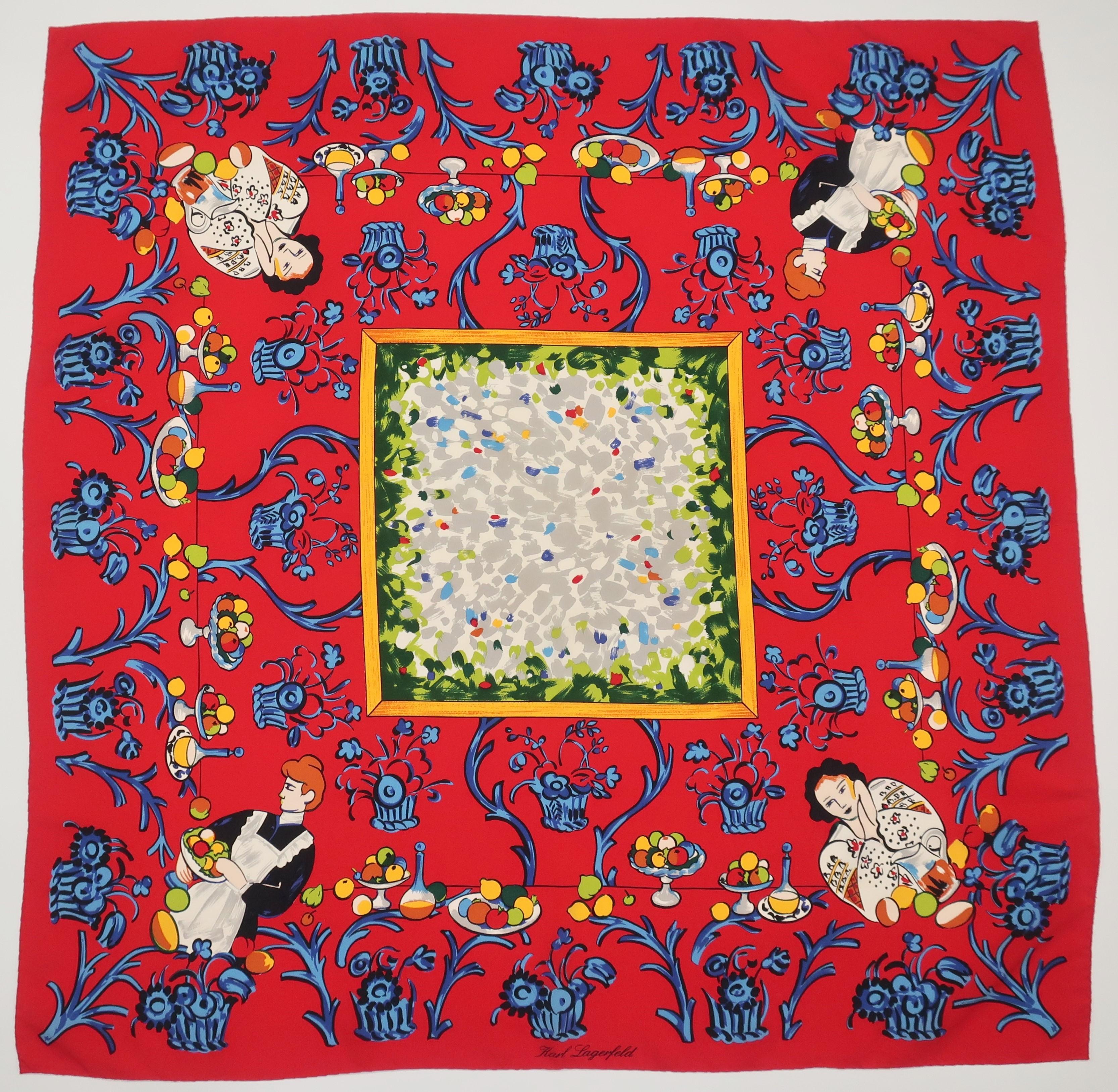 Karl Lagerfeld red silk scarf with images of women, fruit, flowers and wine in shades of blue, green, white, black and yellow.  The design has a beautiful country French aesthetic.  'Karl Lagerfeld' is incorporated into the print with no additional