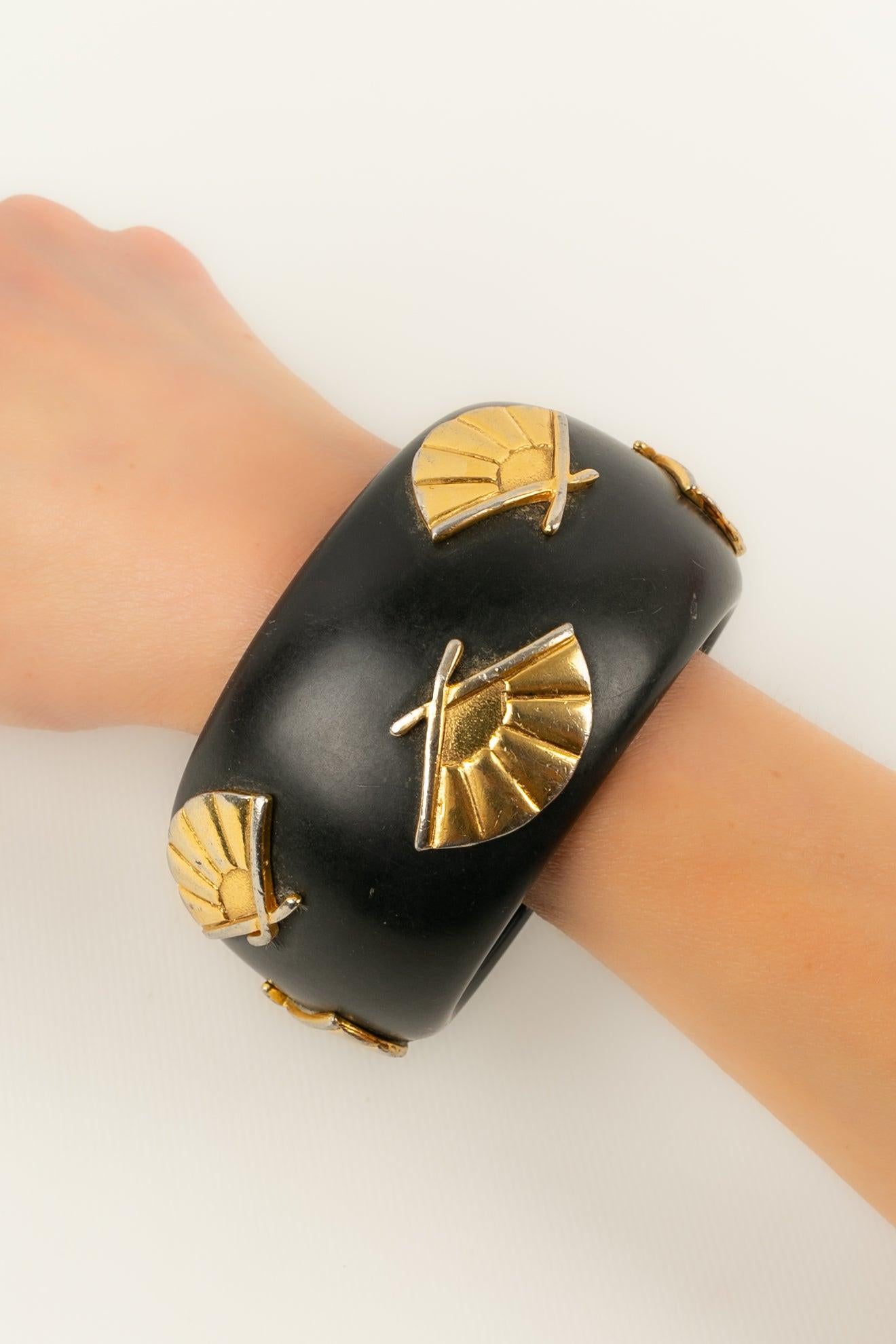 Lagerfeld - Bracelet in black bakelite ornamented with fans in gold-plated metal.

Additional information:
Condition: Good condition
Dimensions: Wrist circumference: 19 cm

Seller Reference: BRA177
