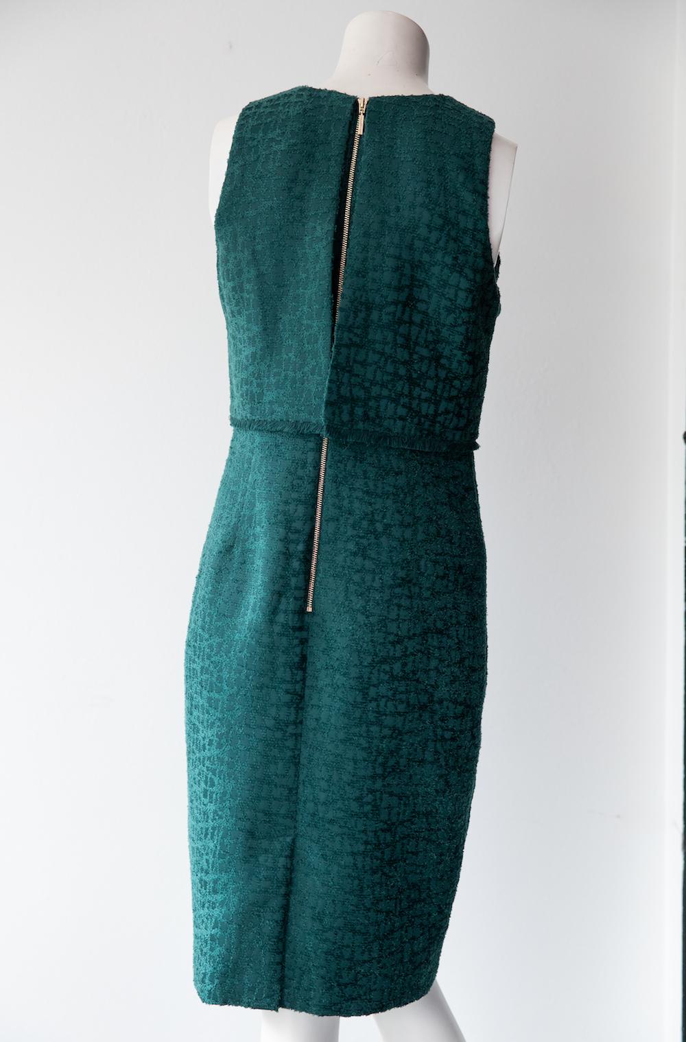 Emerald green shift dress by Karl Lagerfeld. The fabric has a slight shine and raised texture which gives a tweed effect. Waist-panels are finished with a raw hem, and are open at back. Thick gold back zipper completes the dress. 

Size US 2