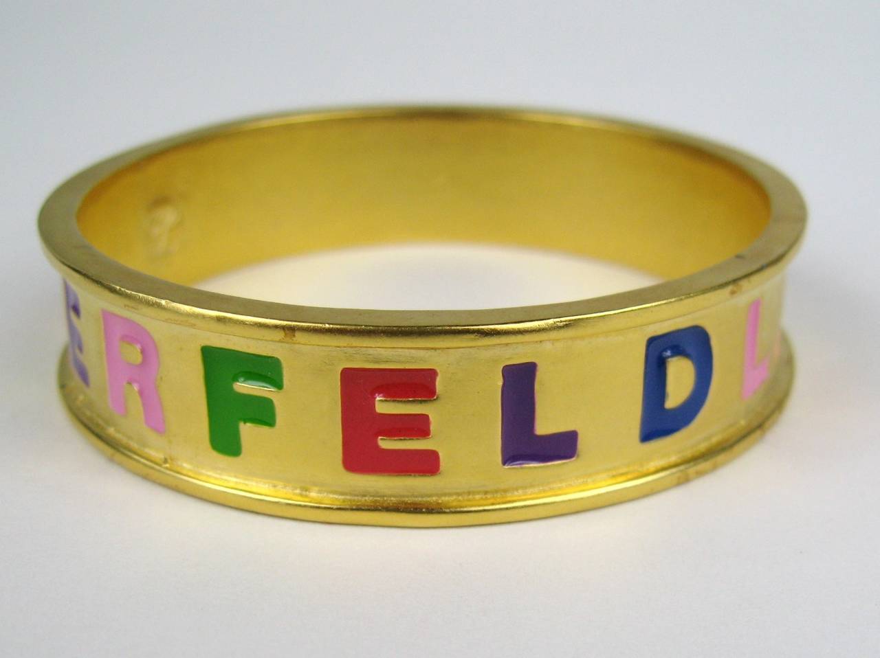 Bangle has large block lettering LAGERFELD. Measuring .66 inches wide Inside diameter 2.69 in Colors of purple, pink, green, red and orange make up the lettering. Necklace, Earrings, charm Bracelet and Bangle are all listed on our storefront. This