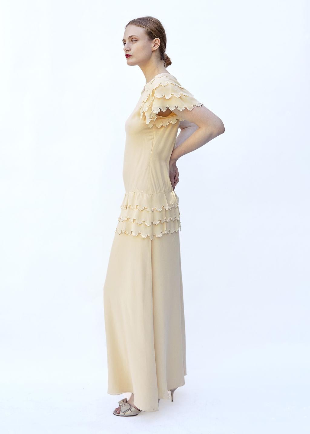 Featured in the 1981 collection by Karl Lagerfeld for Chloe, this Custard Ruffled Dress boasts a drop waist and triple ruffled tiers for a unique and elegant look. Made of luxurious silk fabric, with short ruffled sleeves, this dress exudes