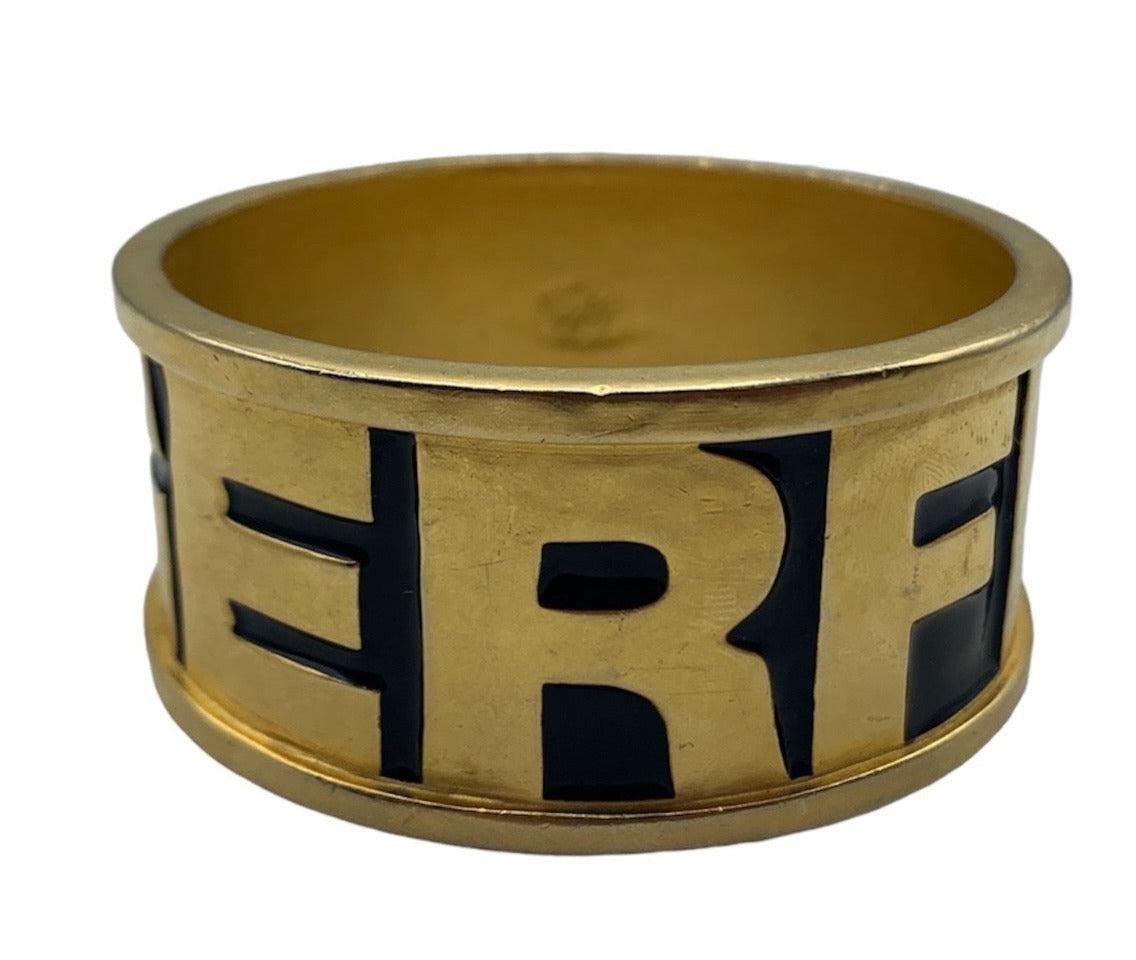 Un pezzo raro e iconico del grande e compianto Karl Lagerfeld. Bracciale pesante in oro con smaltatura nera, anni '90 circa.  che circonda il nome del designer. In ottime condizioni, con un'usura commisurata all'età - ha una bella