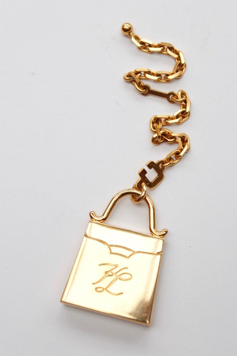 Karl Lagerfeld – Keyring or handbag jewel in gilded metal. 

Additional information: 
Dimensions: Bag: 4.5 cm x 3.2 cm (1.77
