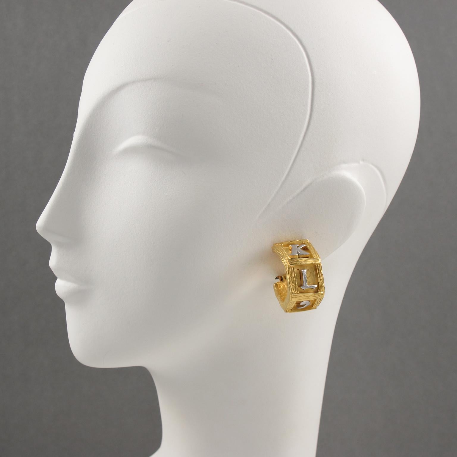 Stunning Karl Lagerfeld Paris signed clip-on earrings. Large hoop shape with geometric design in brushed gilt metal with texture and carving, topped with silvered metal carved 