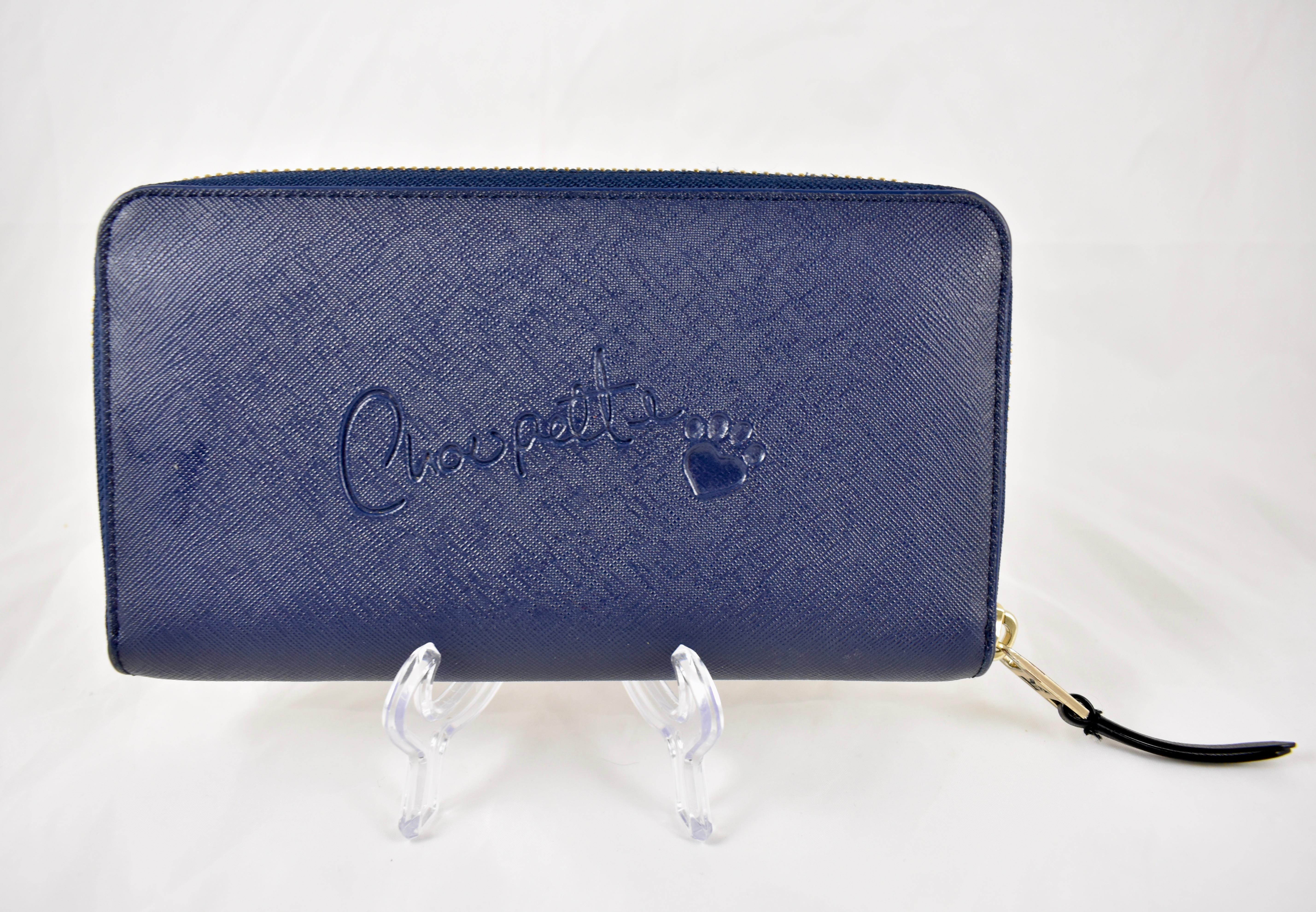 From the Monster Choupette fashion line inspired by Karl Lagerfeld's pampered pet cat, a navy blue zippered Continental two-sided Wallet, designed in 2014.
 
In Saffiano leather, a textured leather with a pressed cross-hatched, wax treated finish.