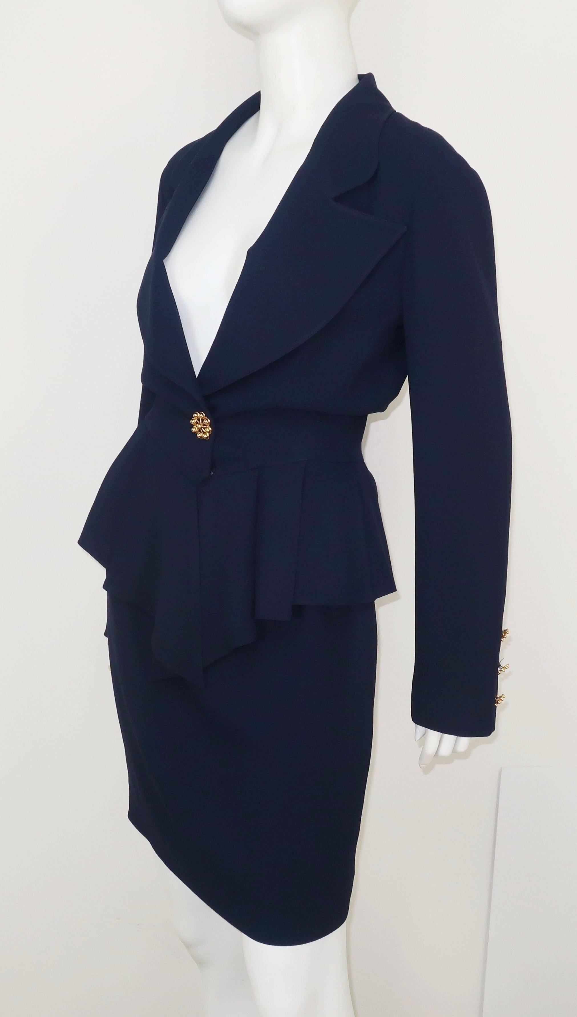 C.1990 Karl Lagerfeld design that combines a feminine peplum silhouette with a classic skirt suit style.  Created with an all season navy blue crepe fabric and accented by eye catching starburst gold buttons at the cuffs and waist.  The jacket