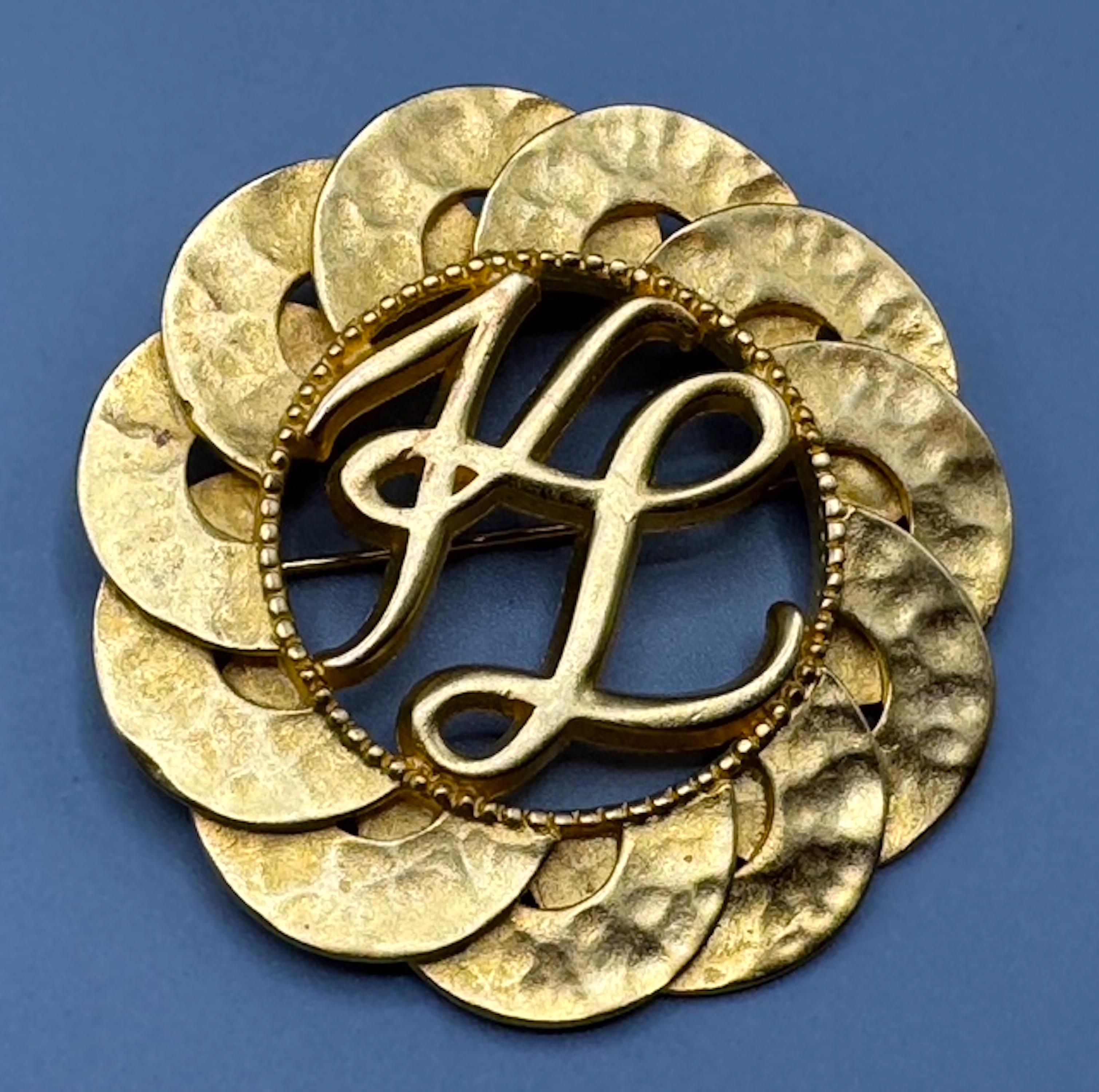 Eine schöne durchbrochene Goldbrosche aus den 1980/90er Jahren von Karl Lagerfeld. Die Stücke mit einem Durchmesser von 2,25 Zoll sind vergoldet und mit einer Jakobsmuschel um die ikonischen, ineinander greifenden Initialen K und L von Karl