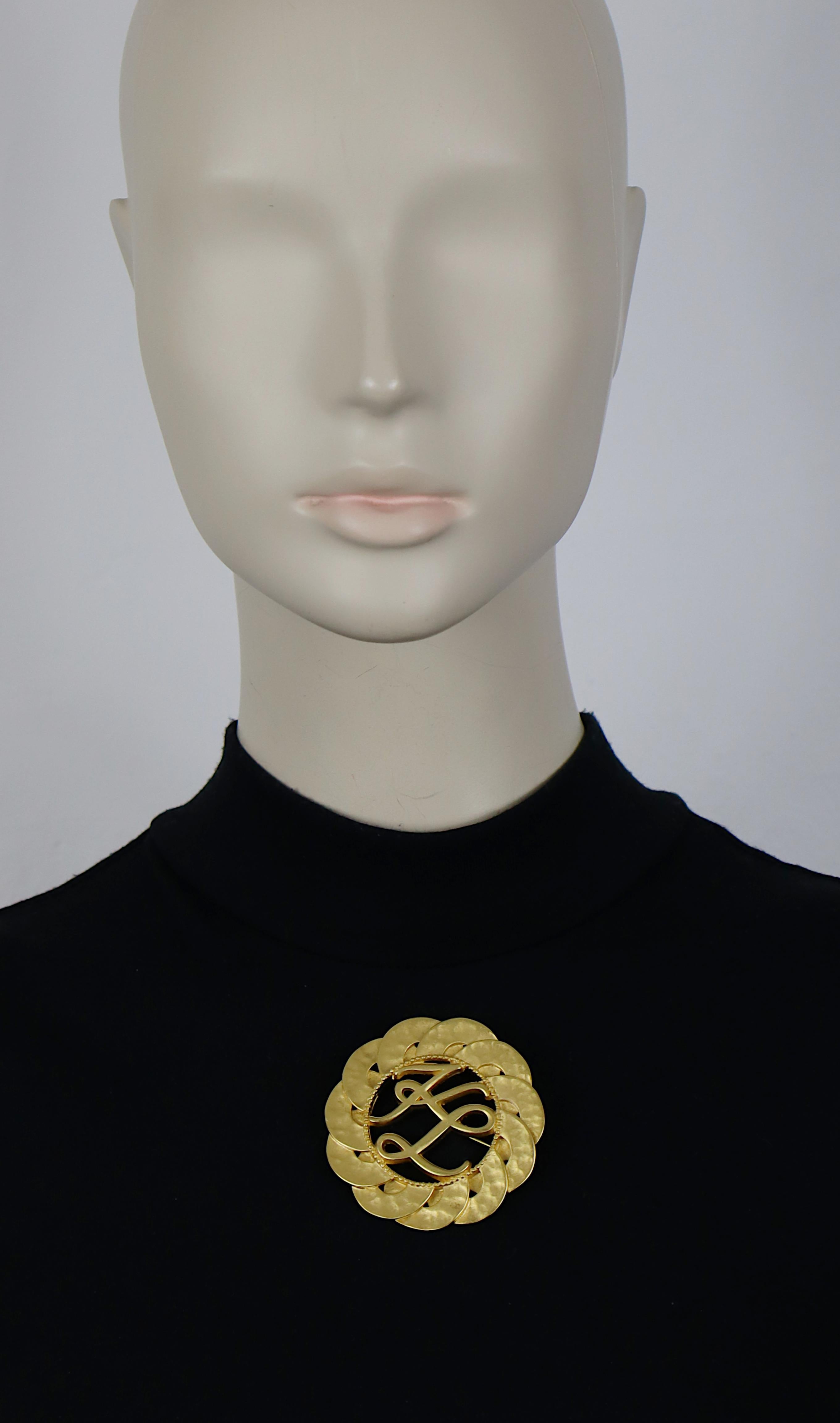 Attributed to KARL LAGERFELD vintage gold tone round brooch featuring the KL logo initials at the center.

UNSIGNED.

Indicative measurements : diameter approx. 5.8 cm (2.28 inches).

Materials : Gold tone metal hardware.

NOTES
- This is a preloved