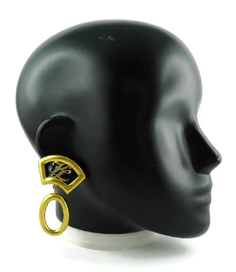 KARL LAGERFELD Vintage ikonische goldfarbene Ohrringe (Clip-on) mit stilisiertem Fächermotiv, verziert mit schwarzer Emaille und KL-Monogramm, ovaler Tropfenring.

Geprägtes KL.

Ungefähre Maße: Länge ca. 6,8 cm (2,68 Zoll) / max. Breite ca. 4,2 cm