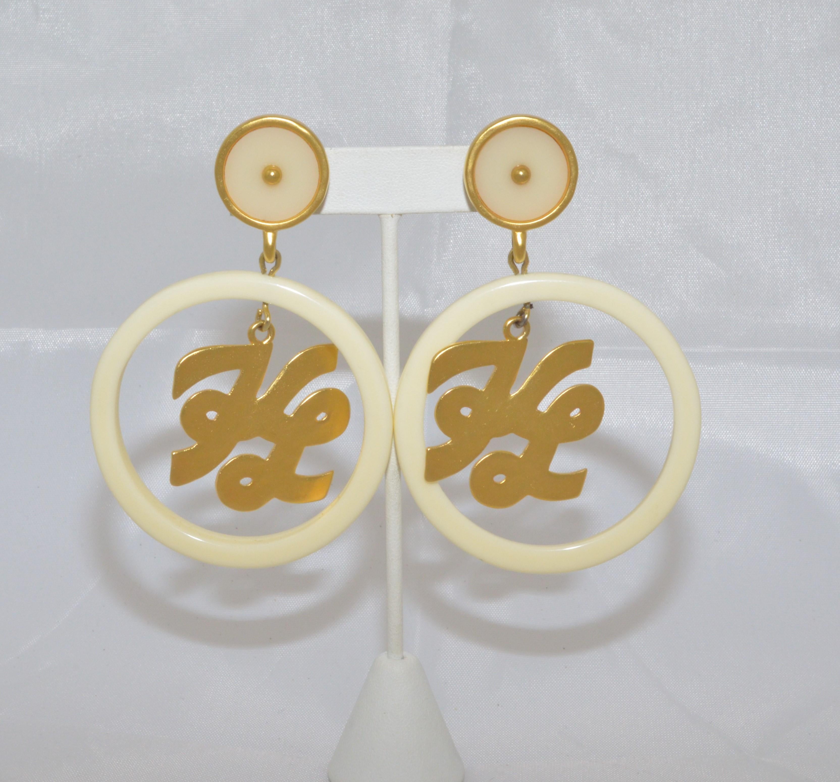 Karl Lagerfeld earrings feature a cream lucite hoop with gold-tone KL initials dangled from the top and a clip on fastening. Earrings are in excellent vintage condition.

Measurement:
Drop - 3.75''
