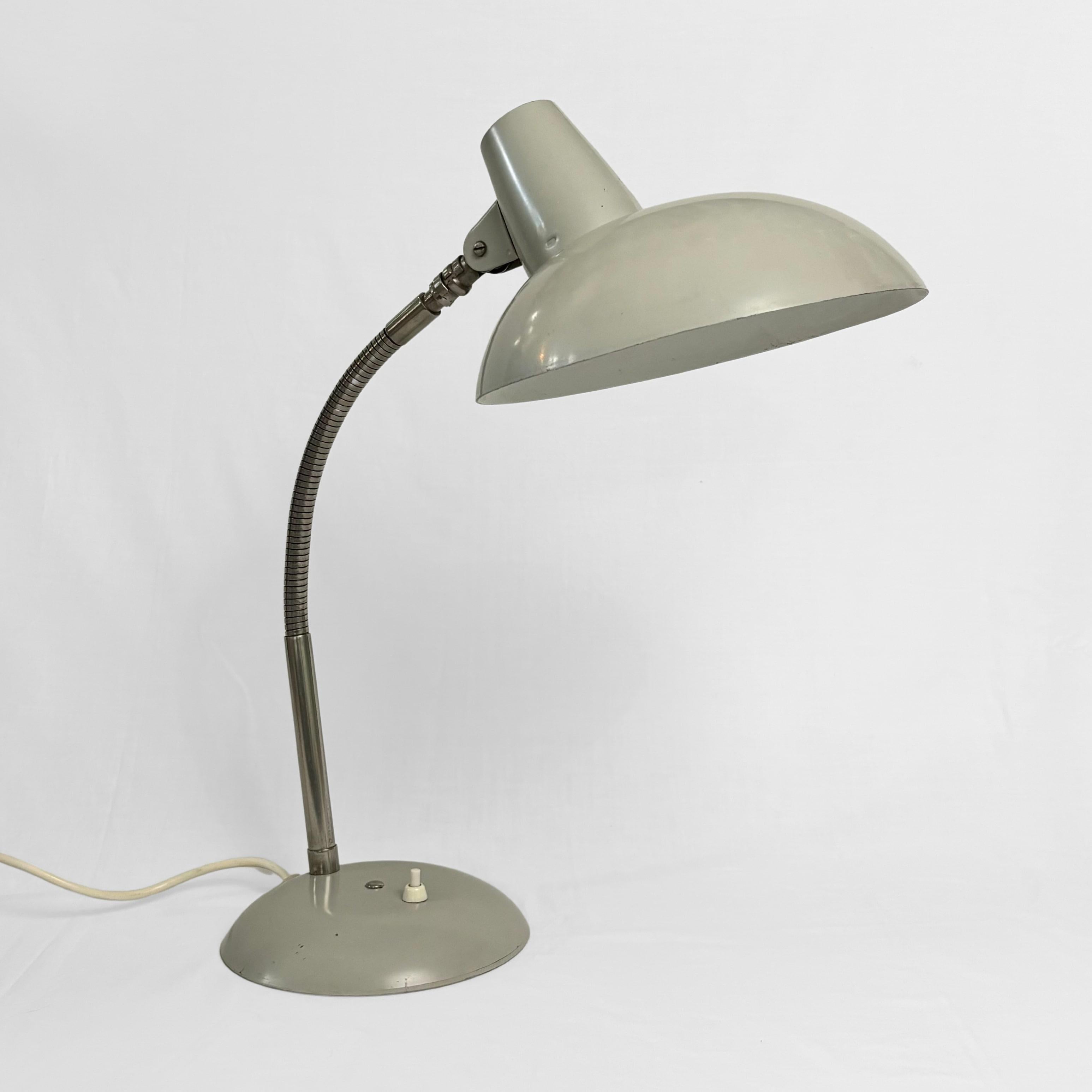A Bauhaus-style table lamp, made from metal with a domed shade, a chrome gooseneck, and a round base fitted with an integrated light switch. Designed by Karl Lang for the German manufacturer SIS Licht in the 1950s.

The manufacturer SIS Licht,