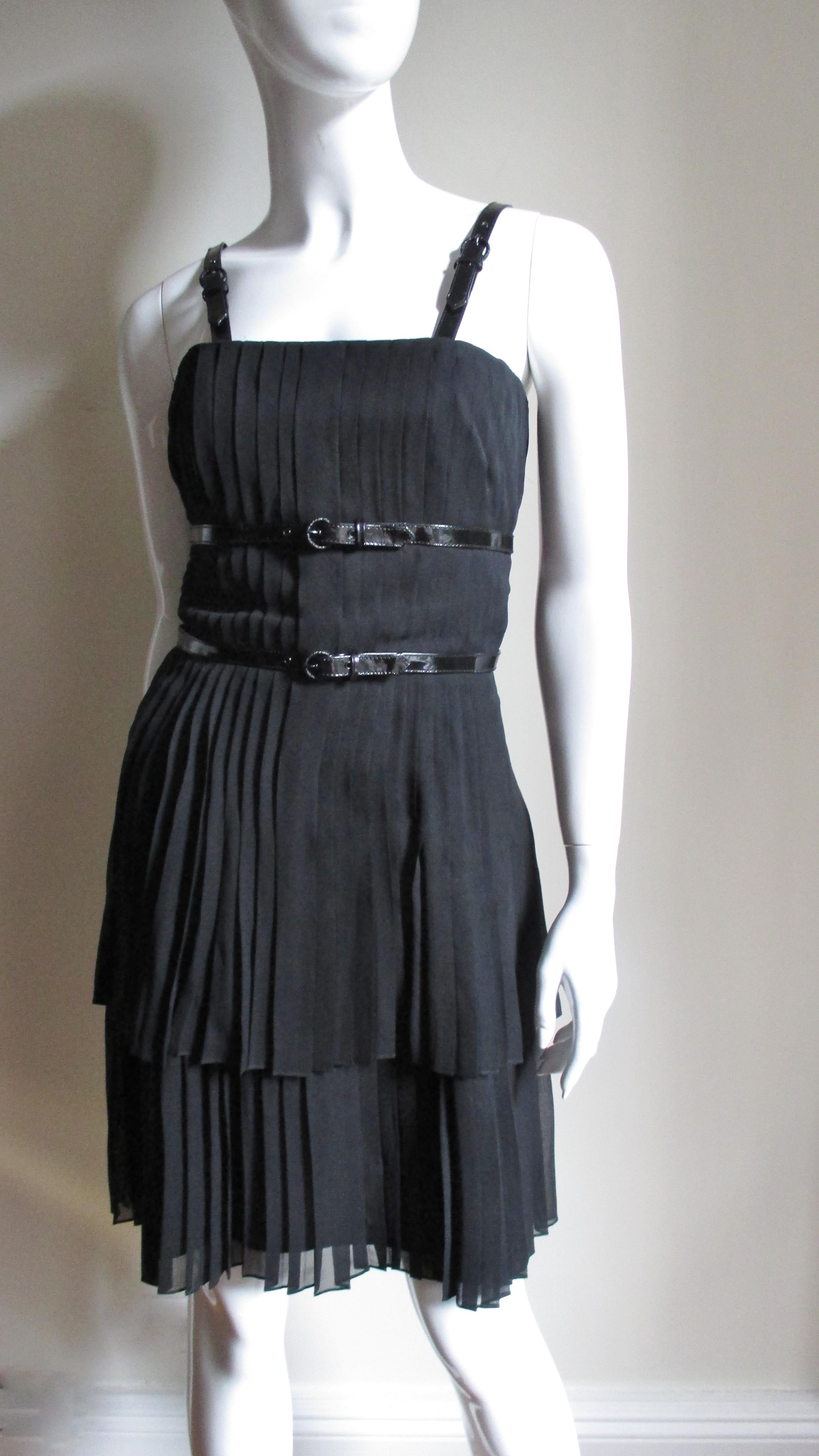 A fabulous black silk dress by Karl Lagerfeld.  It has functional, adjustable buckle black patent straps at the shoulders and around the waist and under bust.  The 2 layer skirt is finely  pleated flaring subtly to the hem.  The dress is fully lined