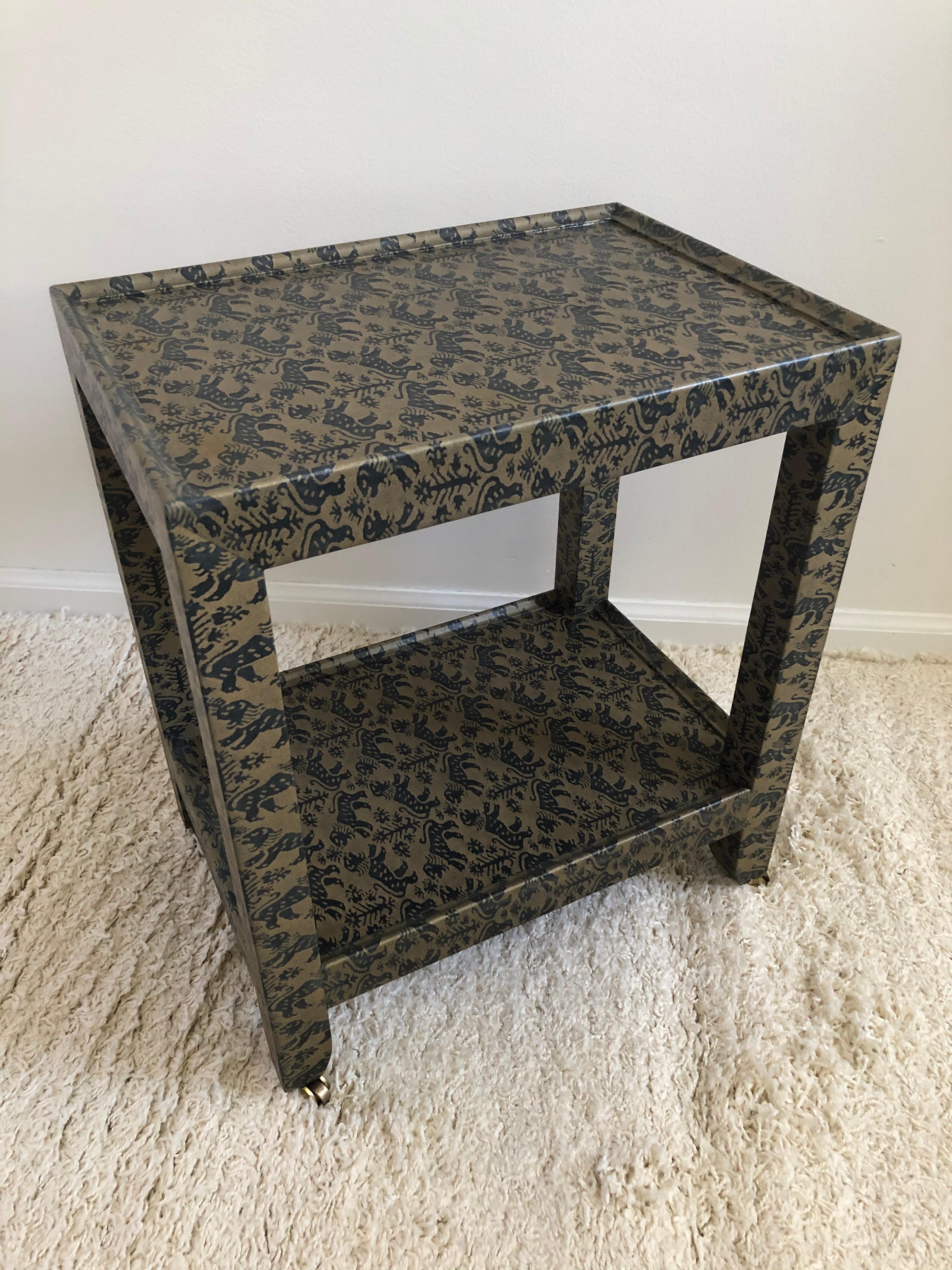 Table à deux niveaux signée et datée Karl Springer, recouverte d'un tissu vert mat et noir imprimé d'animaux Foo Dog, avec roulettes en laiton d'origine.
