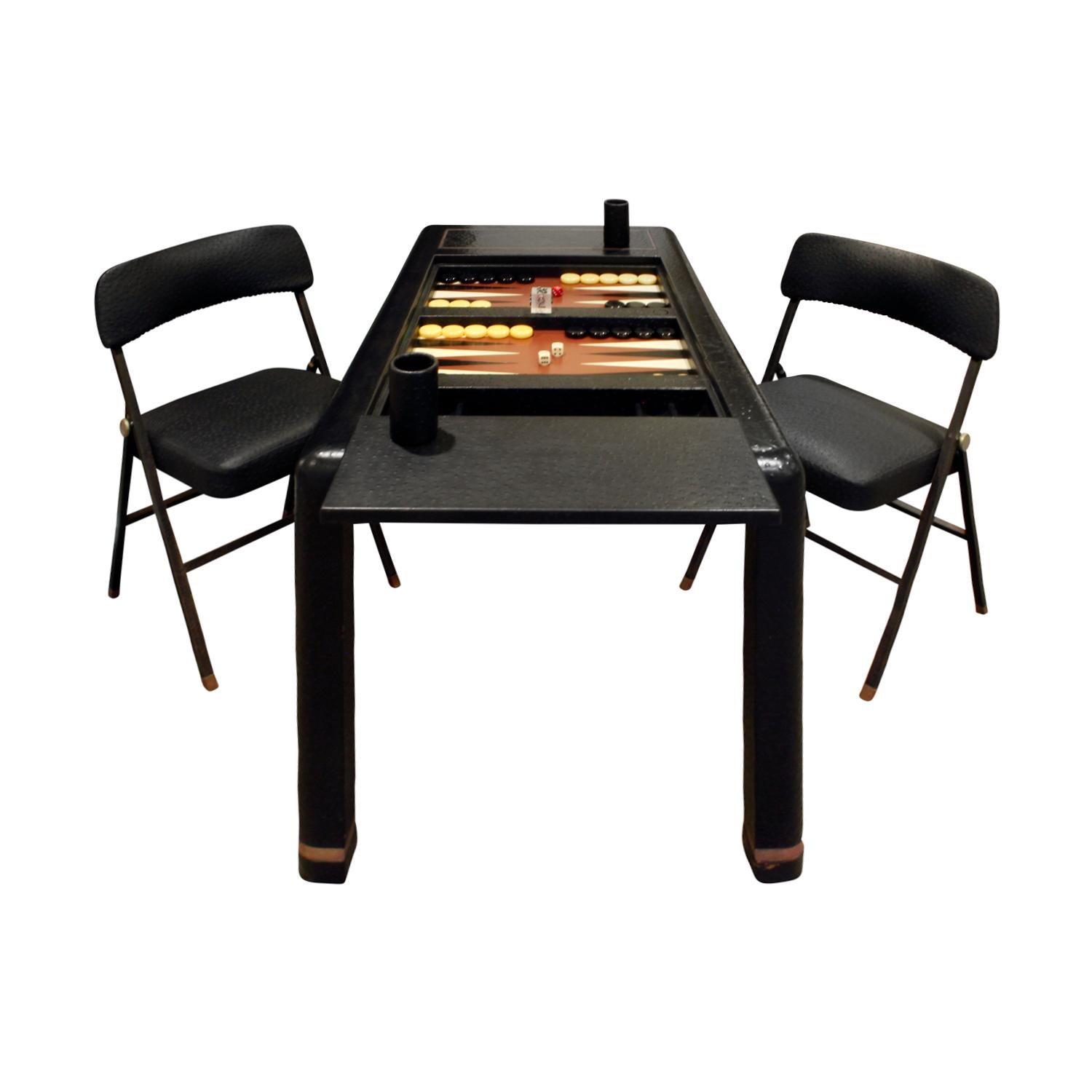 Backgammon table in ostrich skin with brass banding and matching folding chairs in embossed ostrich leather by Karl Springer, American 1970s (signed on bottom with a paper label that reads “Karl Springer”). Game table in leather with original game