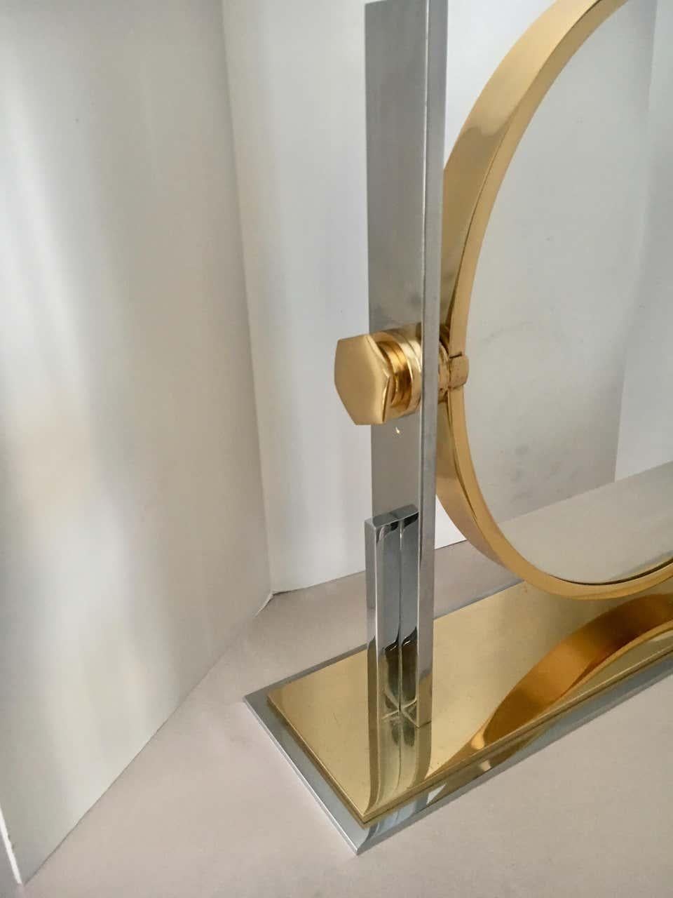 Karl Springer table mirror, a bold statement in polished brass and chrome. A 17.5 inch diameter mirror sits on a very heavy and impressive stand. The mirror tilts to desired angle with side adjustments. The reverse side is also a standard mirror