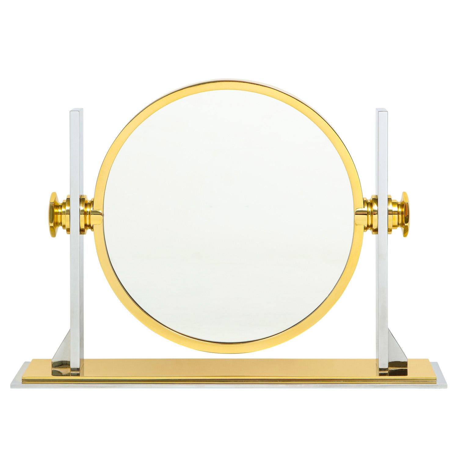 Meticulously crafted vanity/dressing table mirror in polished steel and brass with magnifier on one side and mirror on the other by Karl Springer, American 1980's. This mirror has been completely restored - polished and lacquered.