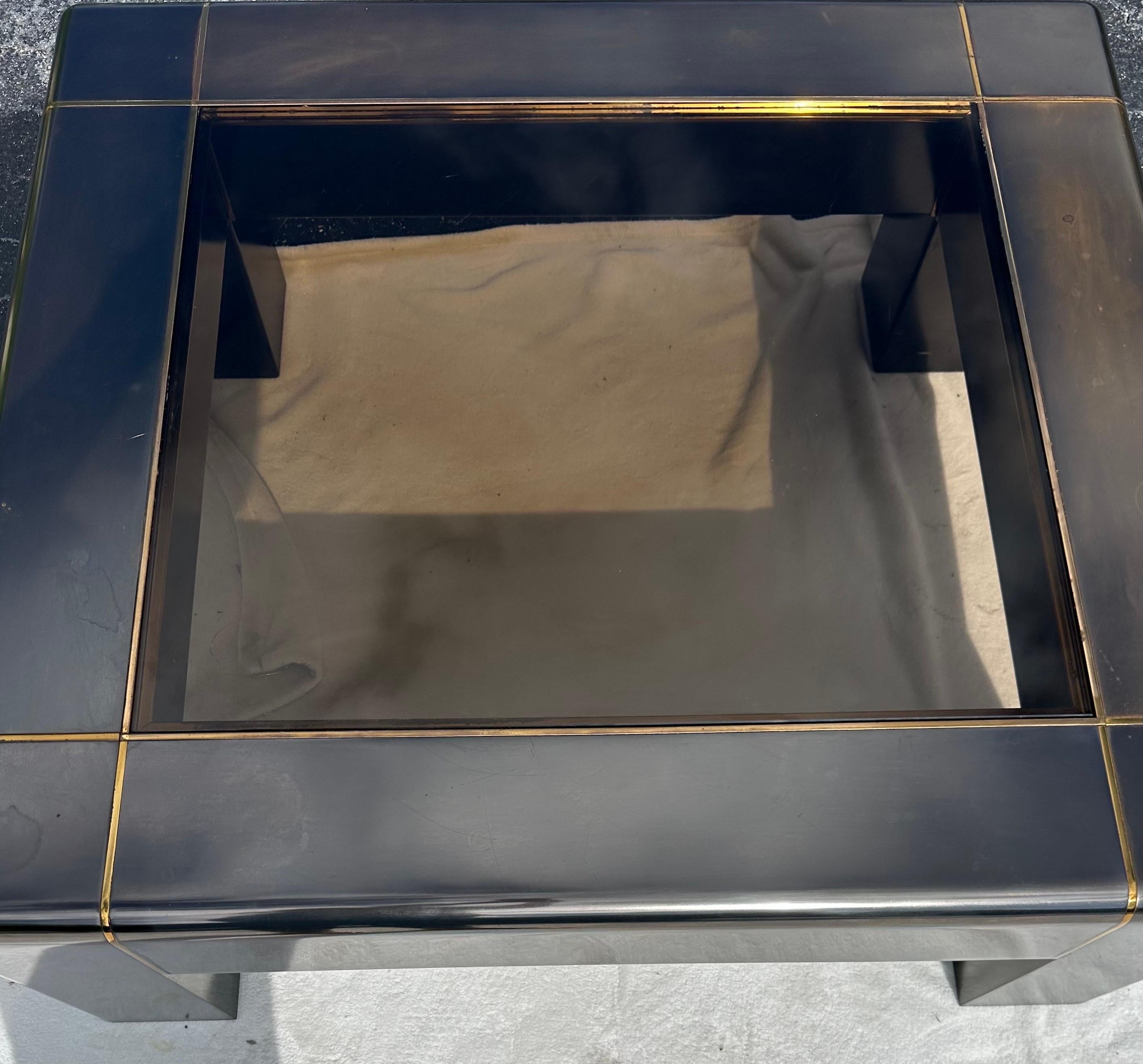 Cette table basse vintage non signée mais qui semble avoir été conçue par Karl Springer est une pièce étonnante de mobilier postmoderne. La finition en laiton gunmetal et le plateau en verre fumé lui confèrent un aspect unique et sophistiqué qui
