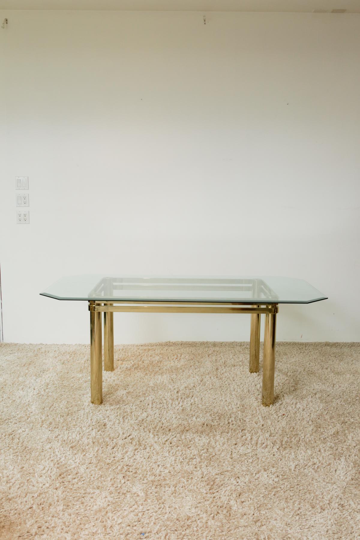 Karl Springer Hollywood Regency style brass and glass dining table

Gorgeous vintage 1970s polished brass base and glass top Hollywood Regency dining table. Designed in the style of Karl Springer. Features a quadrilateral glass with diagonal edges