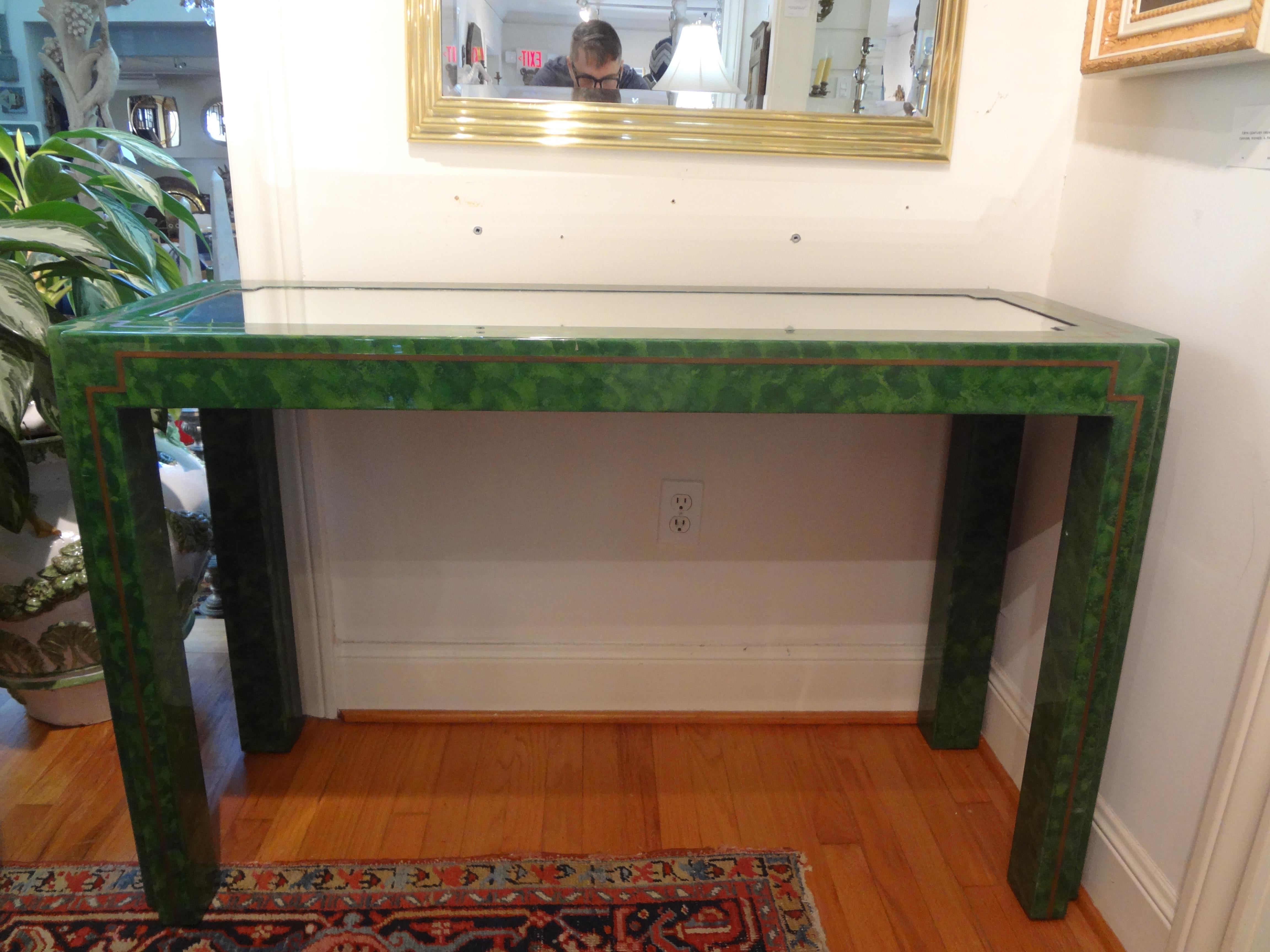 Green lacquer and brass console table. Our outstanding Karl Springer inspired green marbleized lacquer and brass console table with mirrored top is free standing. This versatile and unique free standing Parsons style faux malachite console is